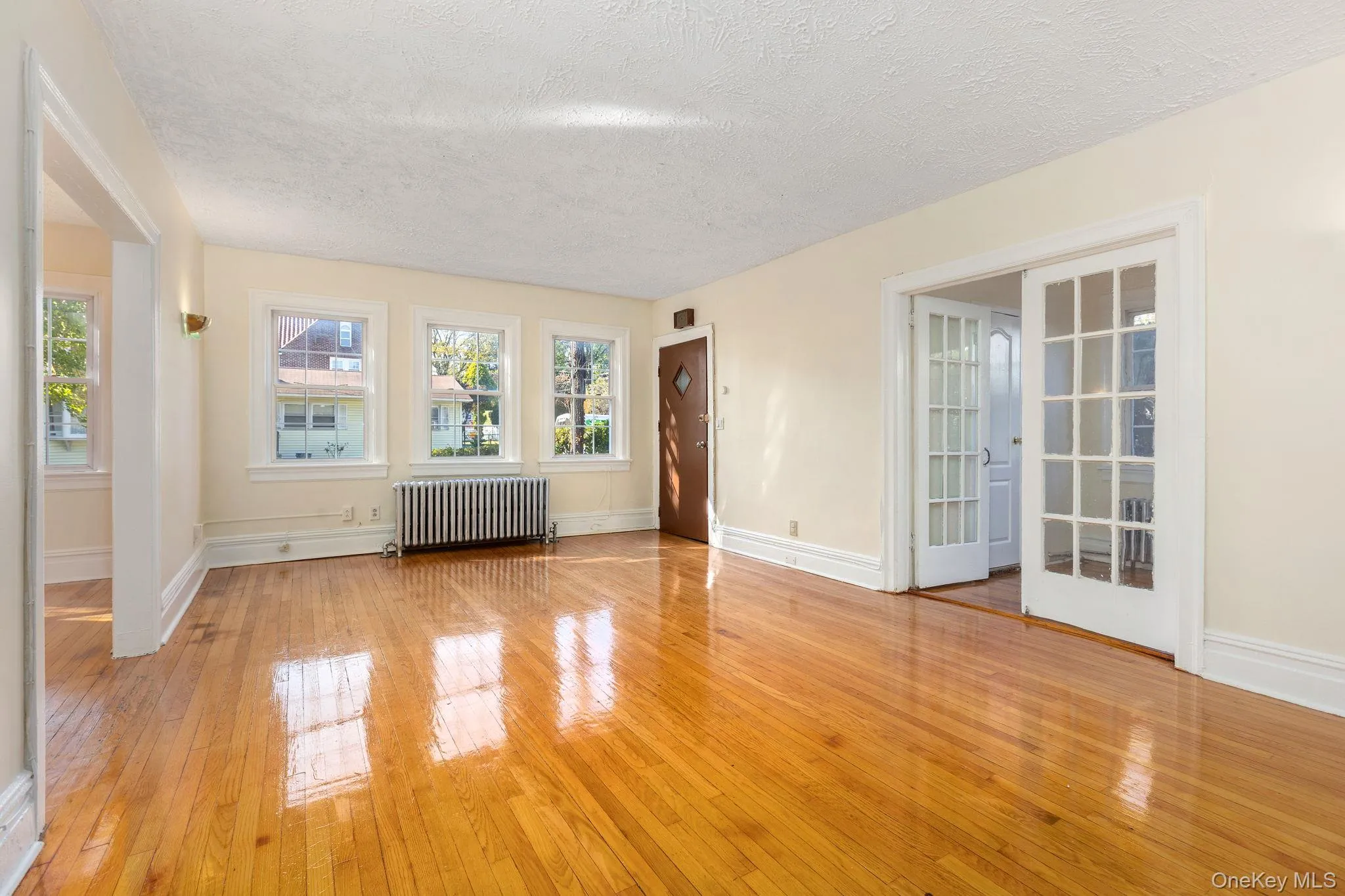 Unfurnished room with light wood-style flooring, radiator, and a textured ceiling Unfurnished room with light wood-style flooring, radiator, and a textured ceiling