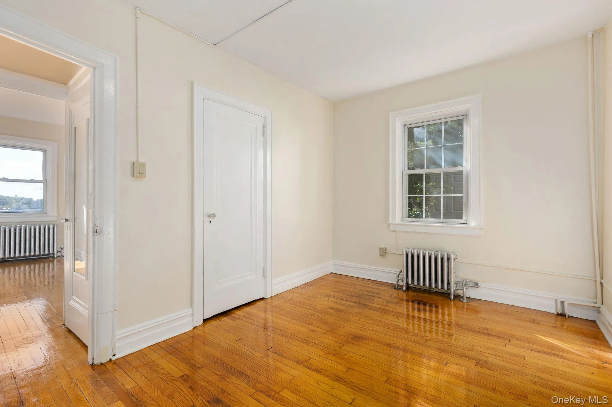 Empty room with light wood finished floors and radiator heating unit Empty room with light wood finished floors and radiator heating unit