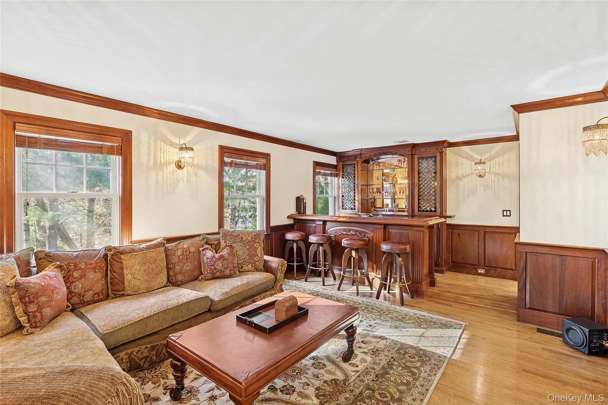 Living room with a wainscoted wall, light wood-style flooring, a bar, crown molding, and wood walls