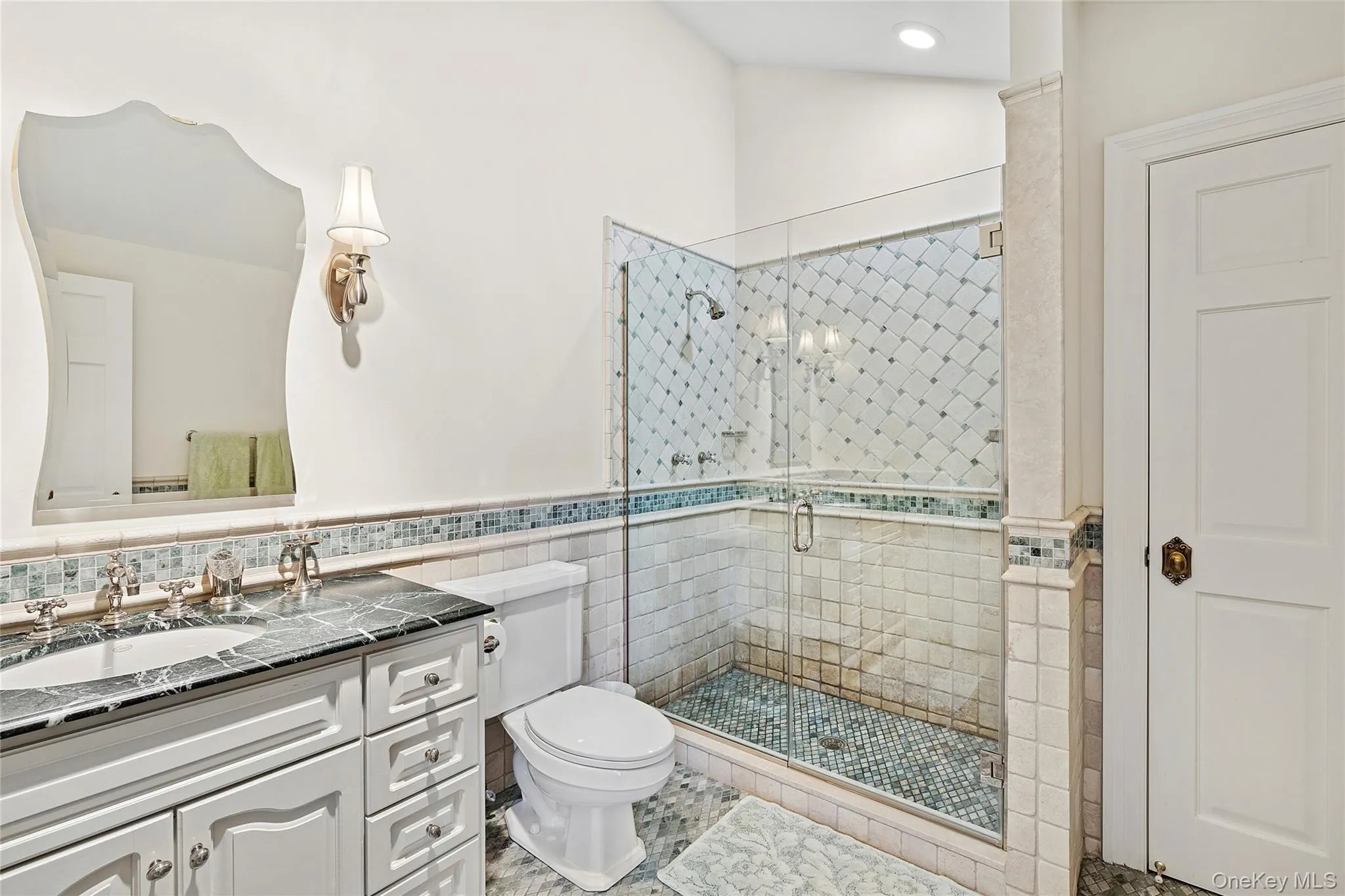 Bathroom featuring vanity, a stall shower, tile walls, wainscoting, and vaulted ceiling