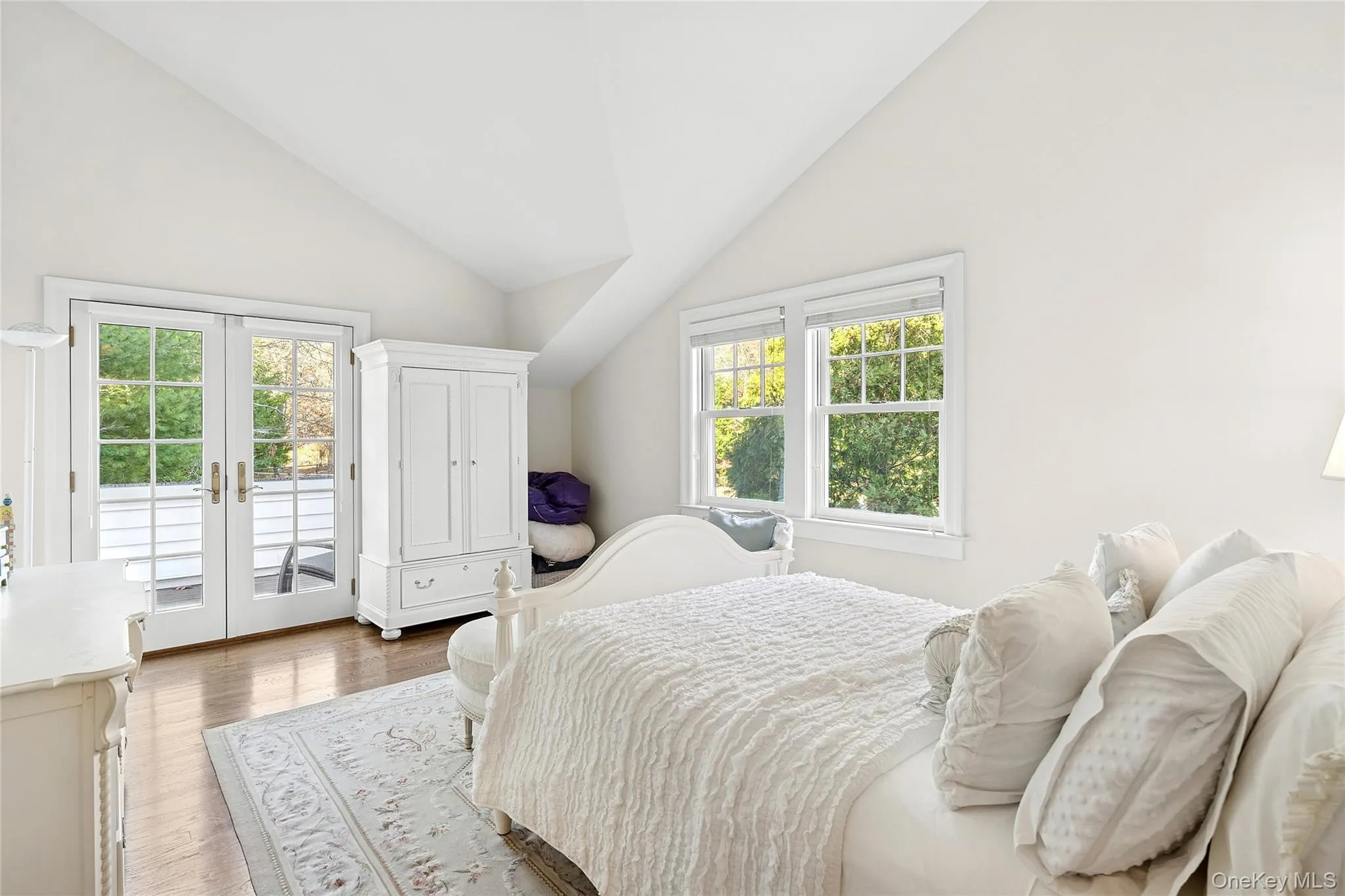 Bedroom with french doors, vaulted ceiling, access to exterior, wood finished floors, and multiple windows