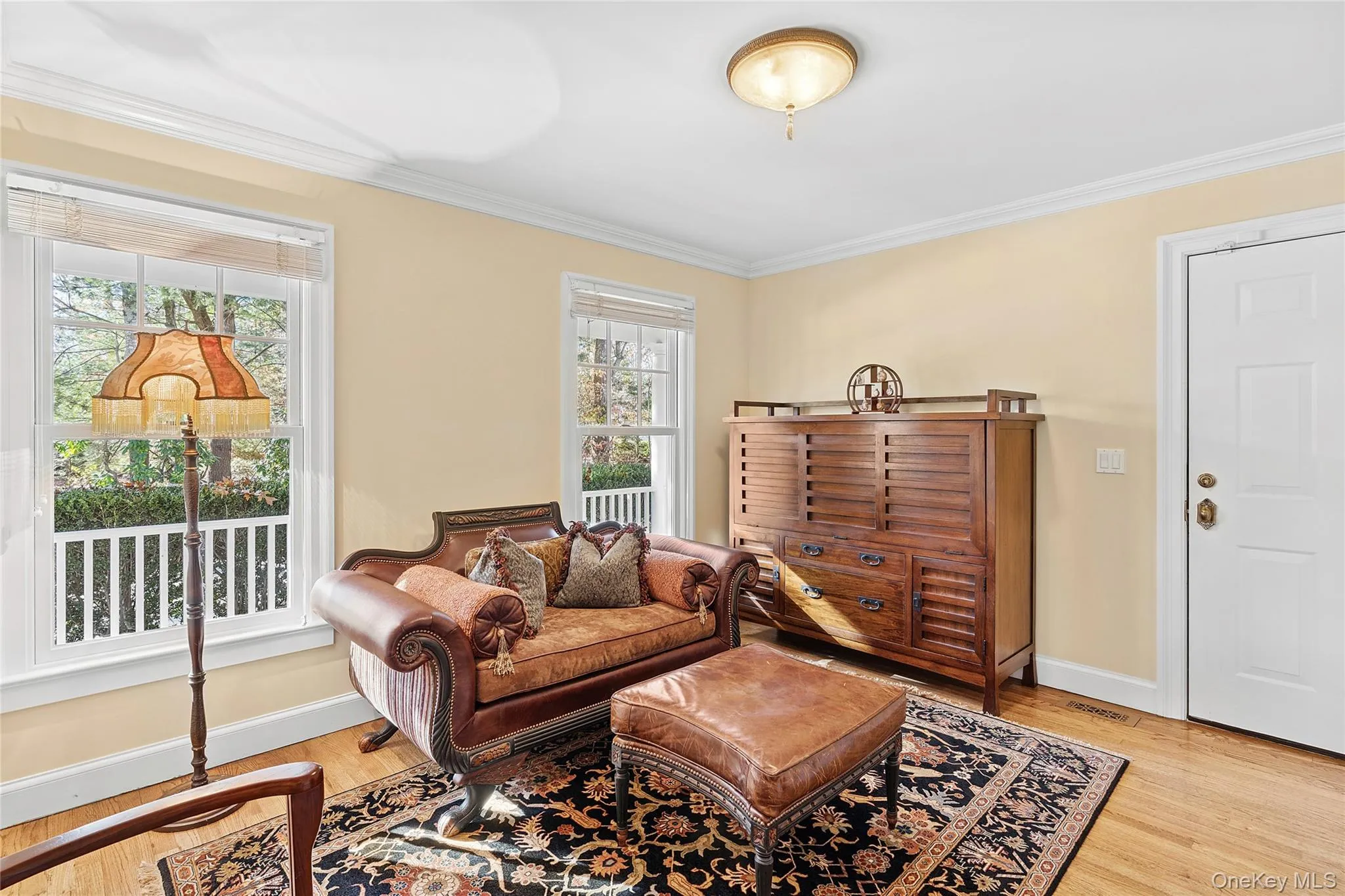 Living area with plenty of natural light, light wood finished floors, and ornamental molding