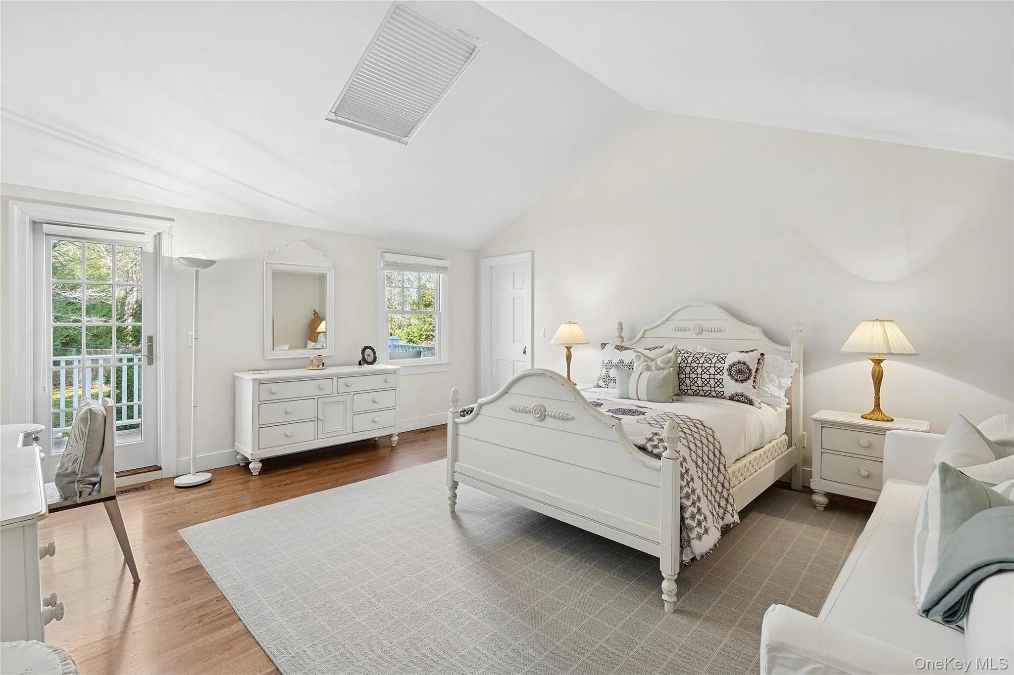 Bedroom with vaulted ceiling, wood finished floors, and access to exterior
