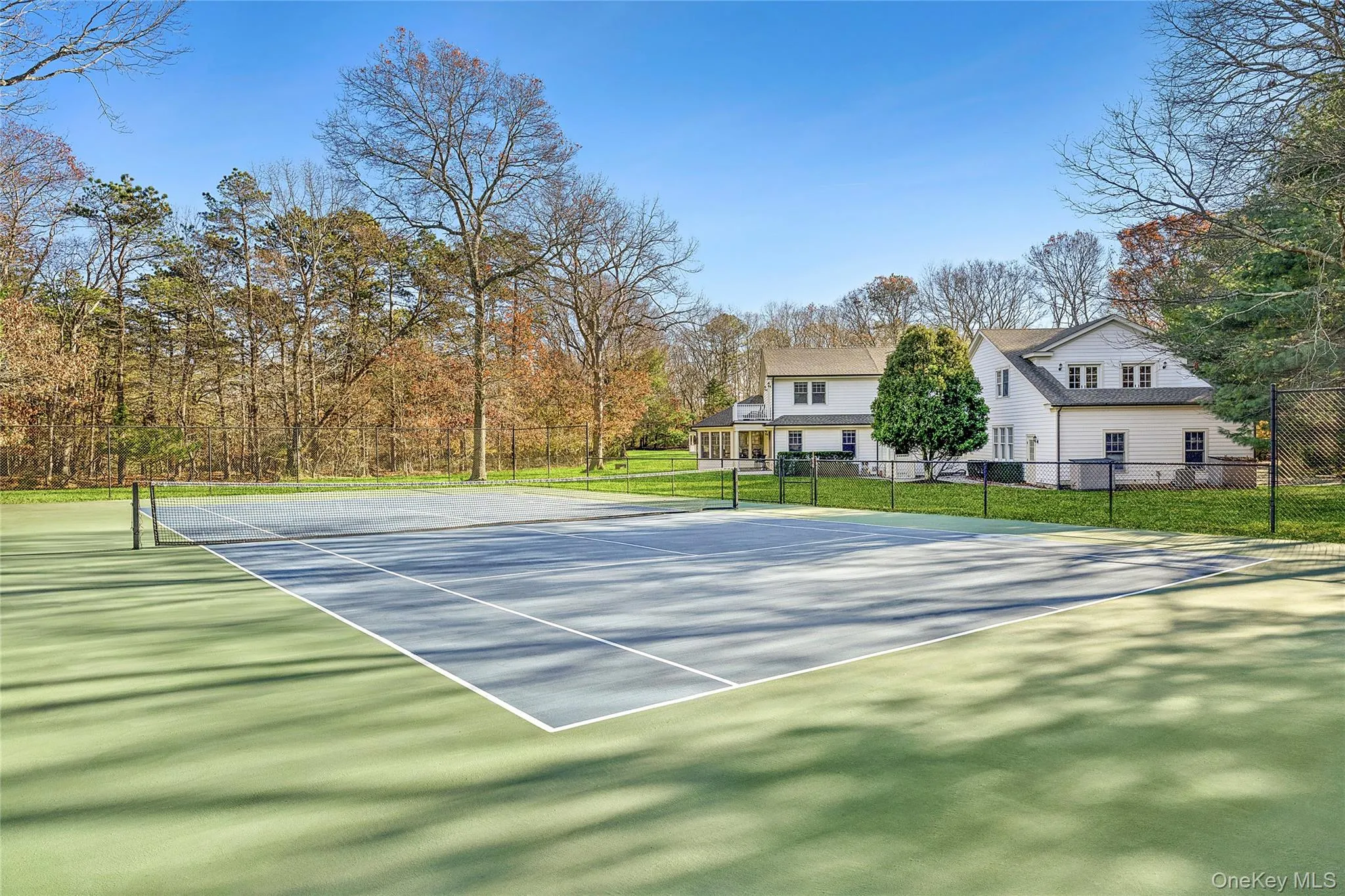 View of tennis court with view of wooded area