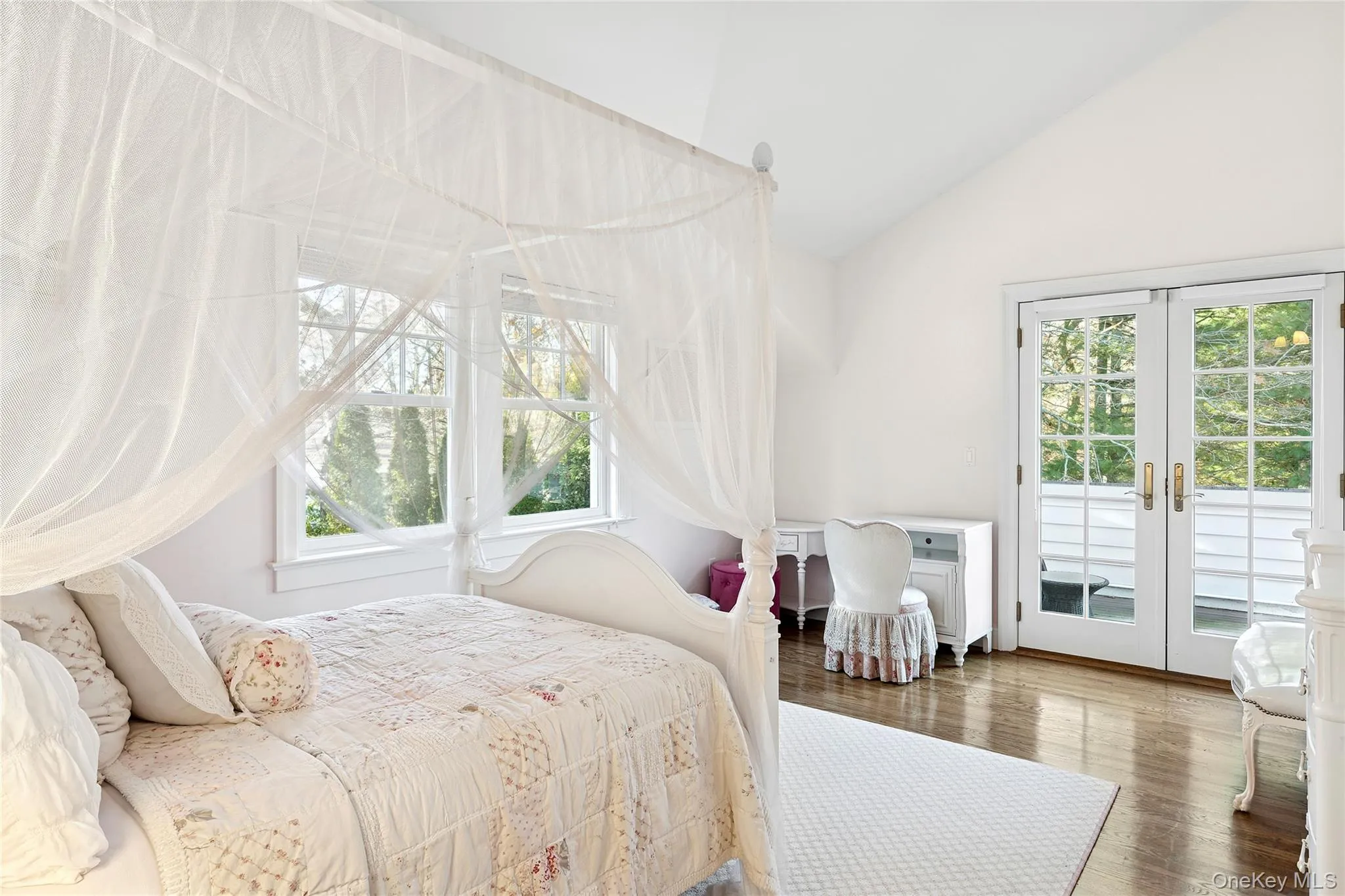 Bedroom featuring french doors, access to outside, wood finished floors, multiple windows, and high vaulted ceiling