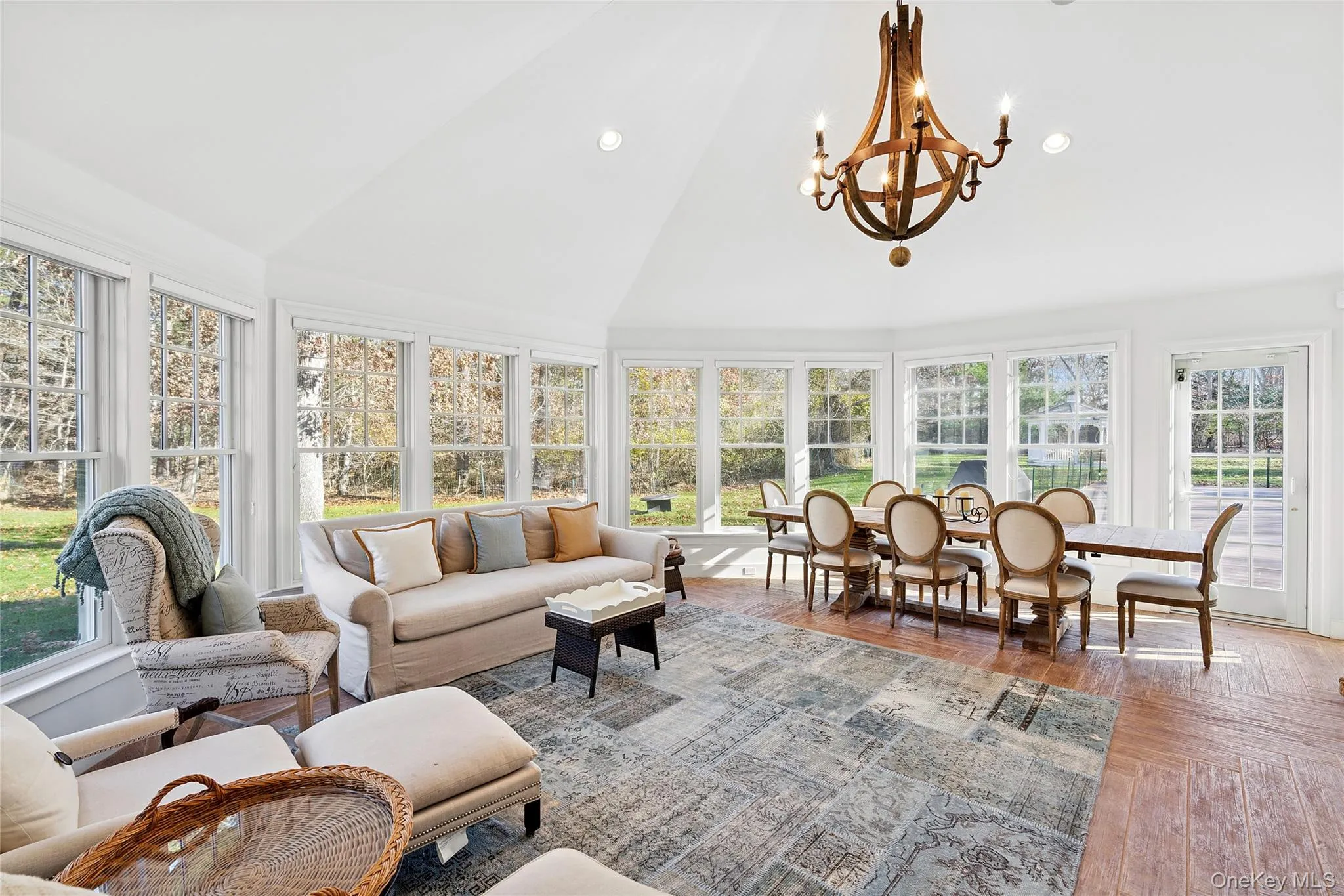 Sunroom with high vaulted ceiling, plenty of natural light, recessed lighting, and a chandelier