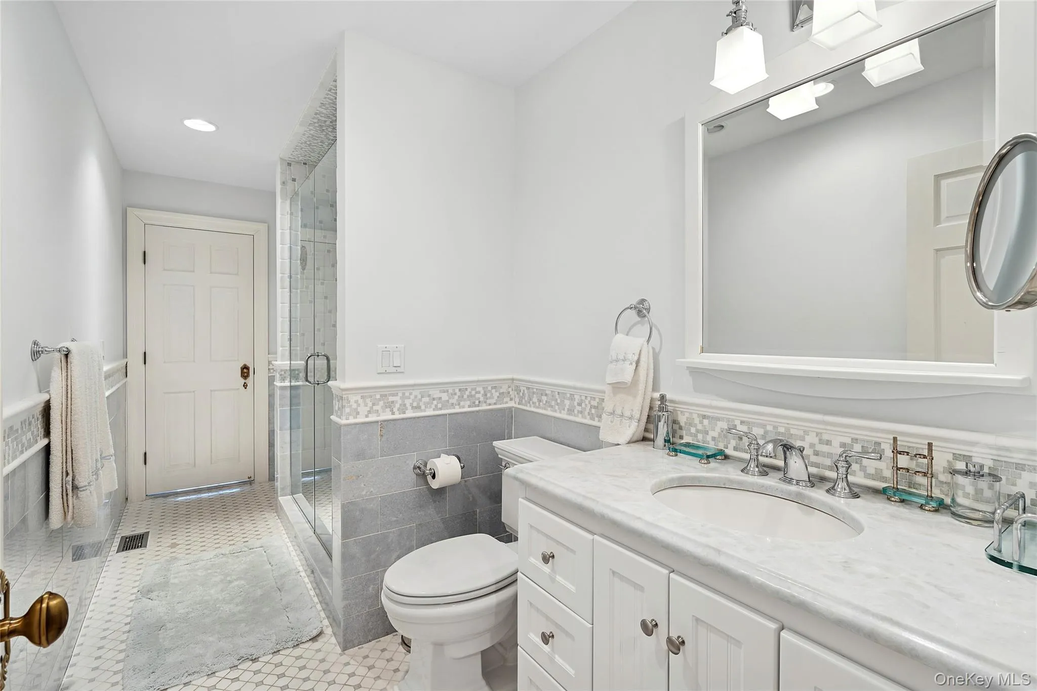 Bathroom featuring a wainscoted wall, tile walls, vanity, a stall shower, and light tile patterned floors