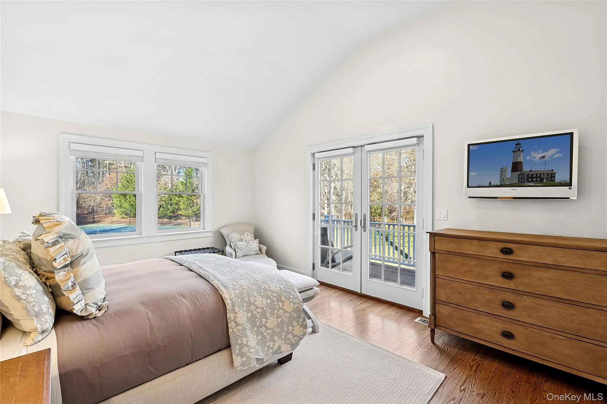Bedroom featuring vaulted ceiling, access to exterior, multiple windows, and wood finished floors