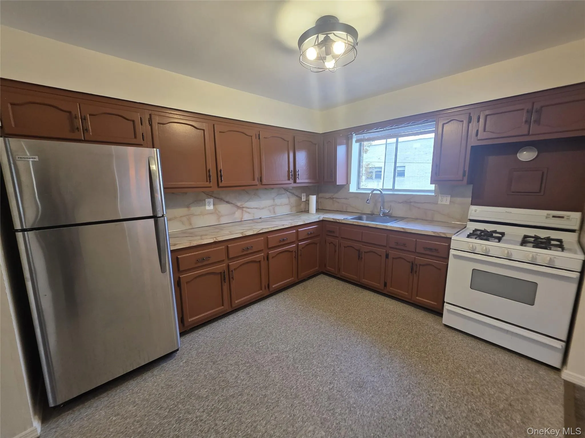 Kitchen featuring freestanding refrigerator, white gas stove, light countertops, and backsplash Kitchen featuring freestanding refrigerator, white gas stove, light countertops, and backsplash