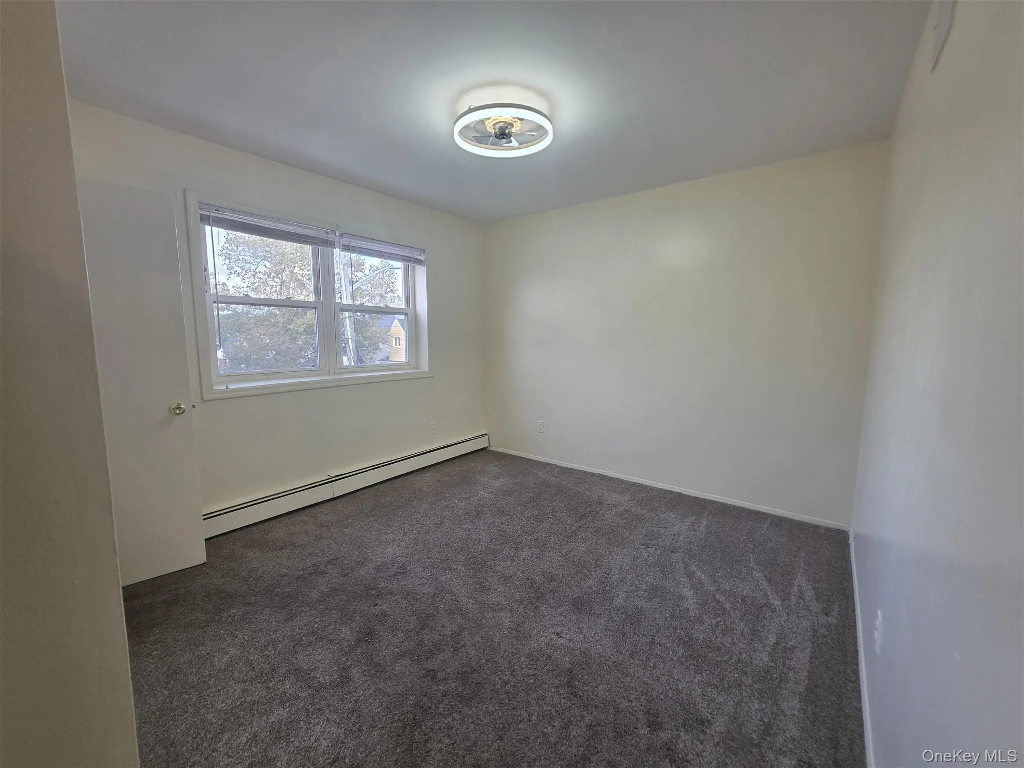 Spare room featuring dark carpet and a baseboard heating unit Spare room featuring dark carpet and a baseboard heating unit