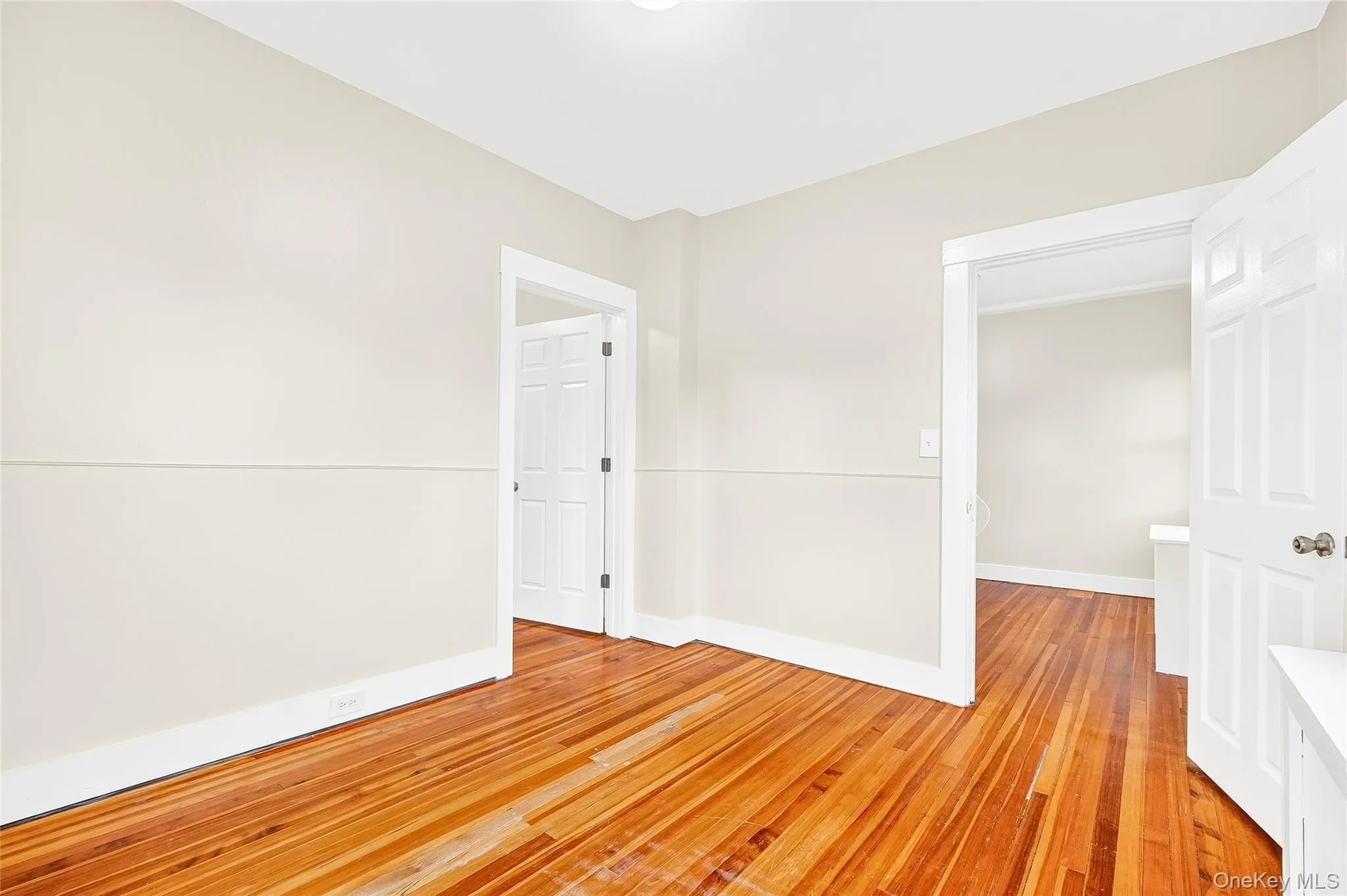 Unfurnished room with light wood finished floors and baseboards Unfurnished room with light wood finished floors and baseboards