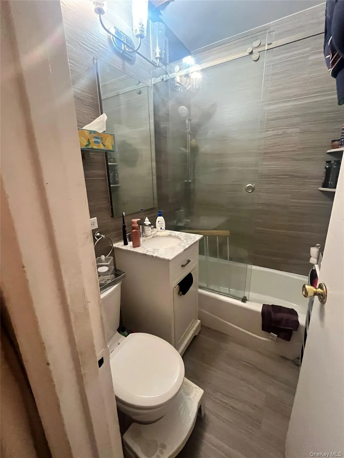 Bathroom featuring vanity, enclosed tub / shower combo, and dark wood finished floors Bathroom featuring vanity, enclosed tub / shower combo, and dark wood finished floors