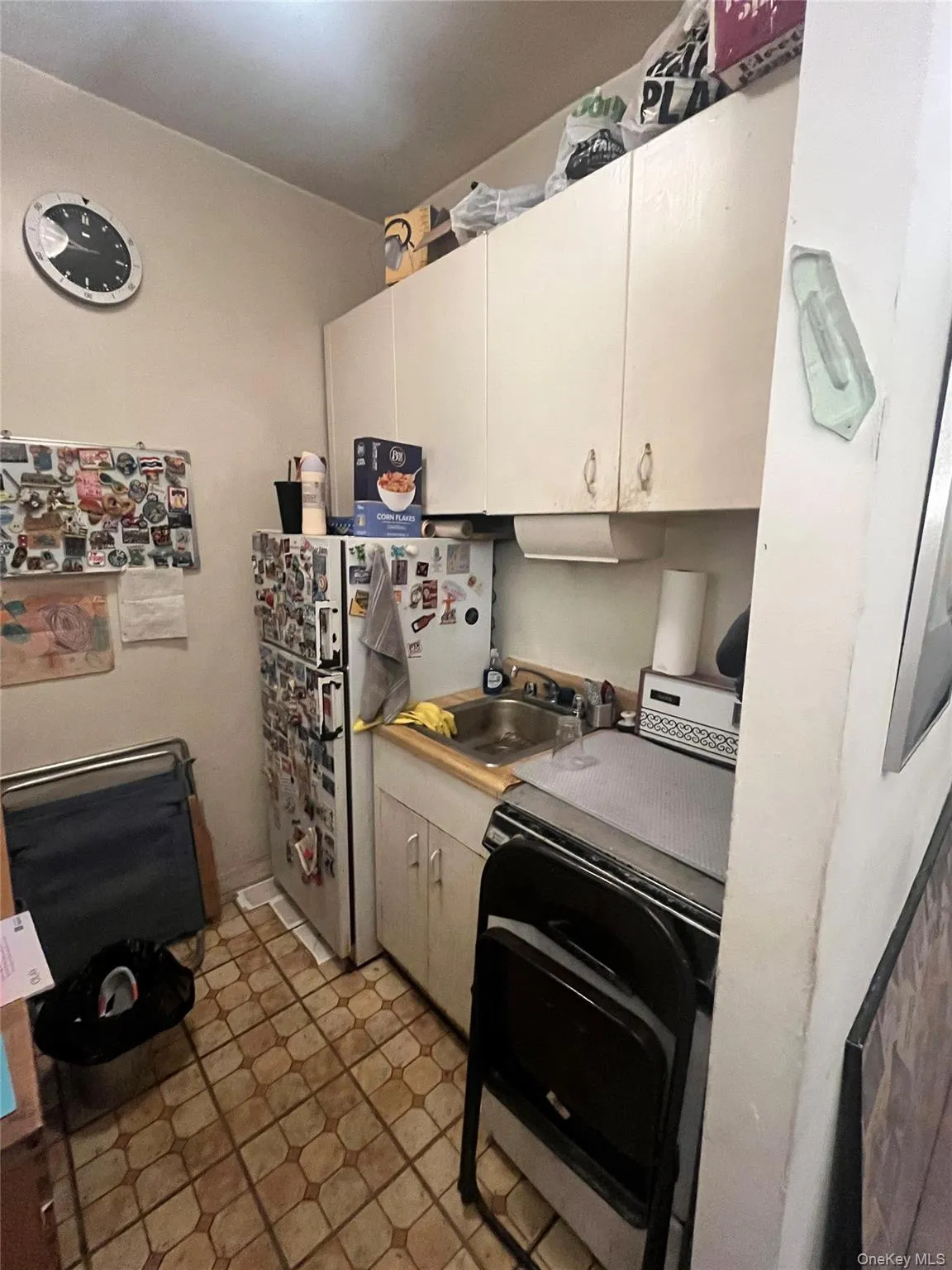 Kitchen featuring freestanding refrigerator, black stove, light countertops, and light tile patterned floors Kitchen featuring freestanding refrigerator, black stove, light countertops, and light tile patterned floors