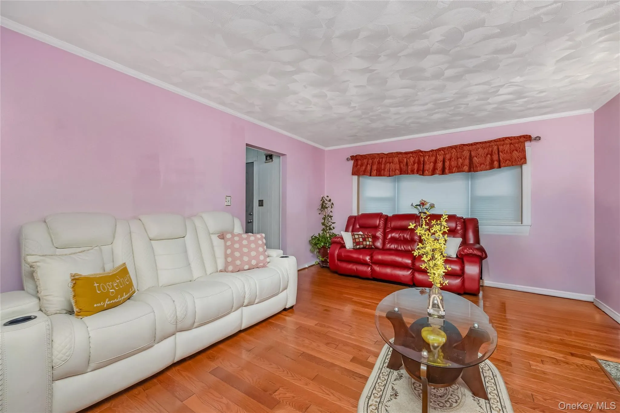 Living area featuring wood finished floors and ornamental molding Living area featuring wood finished floors and ornamental molding