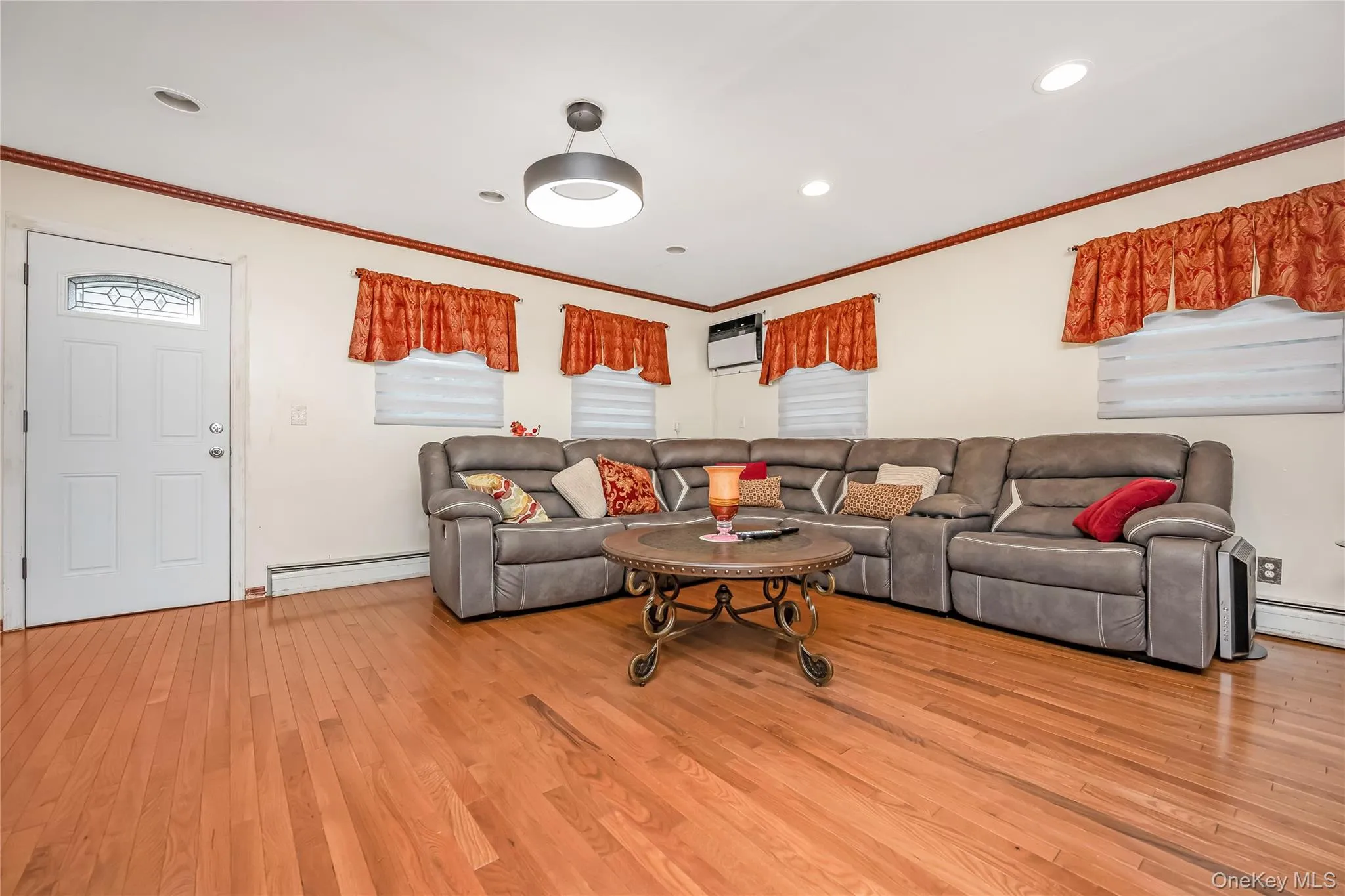 Living room featuring light wood-style floors, ornamental molding, baseboard heating, and recessed lighting Living room featuring light wood-style floors, ornamental molding, baseboard heating, and recessed lighting