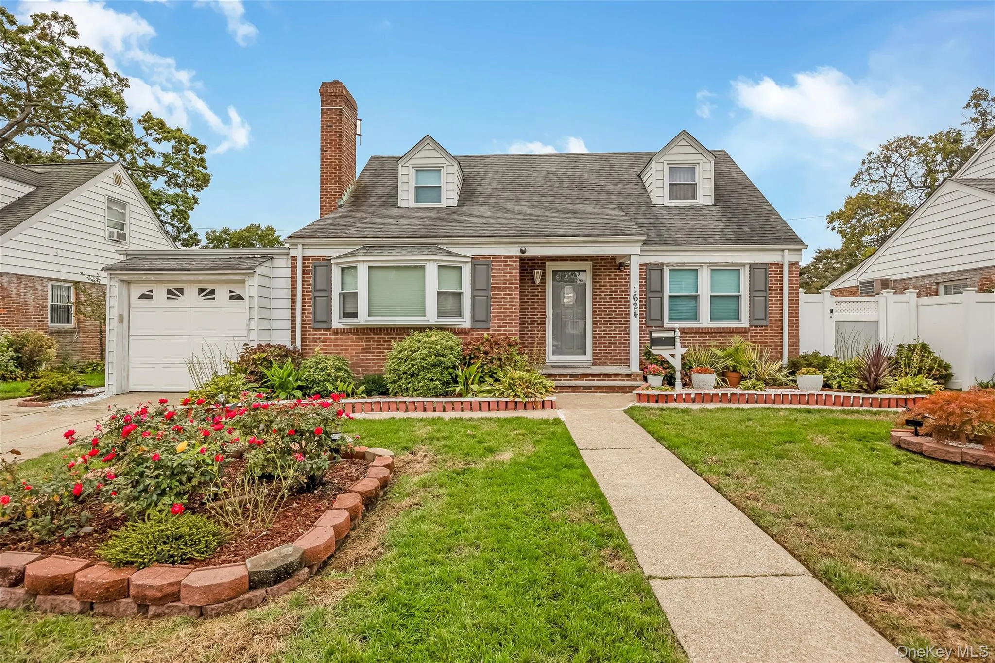 Cape cod home with roof with shingles, brick siding, a chimney, and a garage Cape cod home with roof with shingles, brick siding, a chimney, and a garage