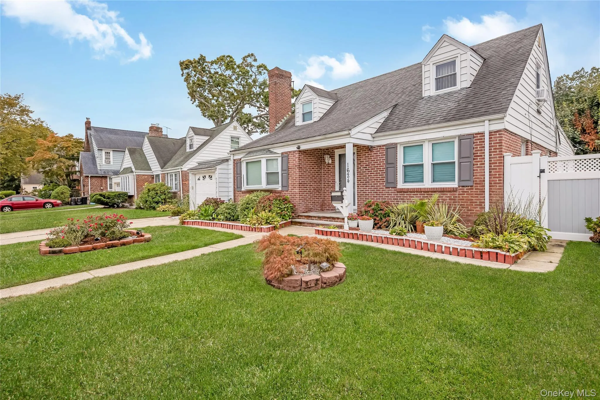 Cape cod-style house featuring brick siding, roof with shingles, a garage, driveway, and a chimney Cape cod-style house featuring brick siding, roof with shingles, a garage, driveway, and a chimney