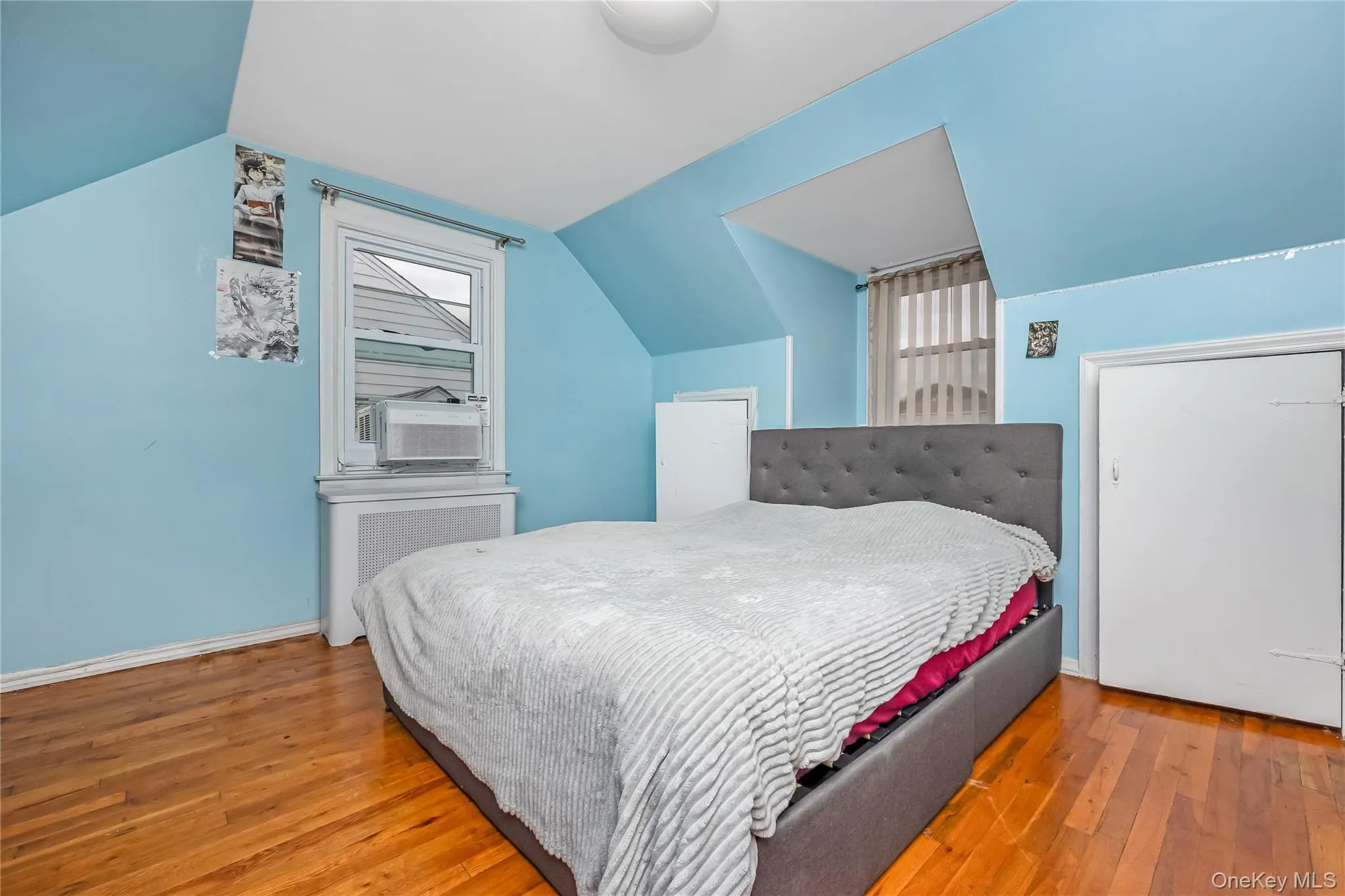 Bedroom with radiator, wood finished floors, and vaulted ceiling Bedroom with radiator, wood finished floors, and vaulted ceiling