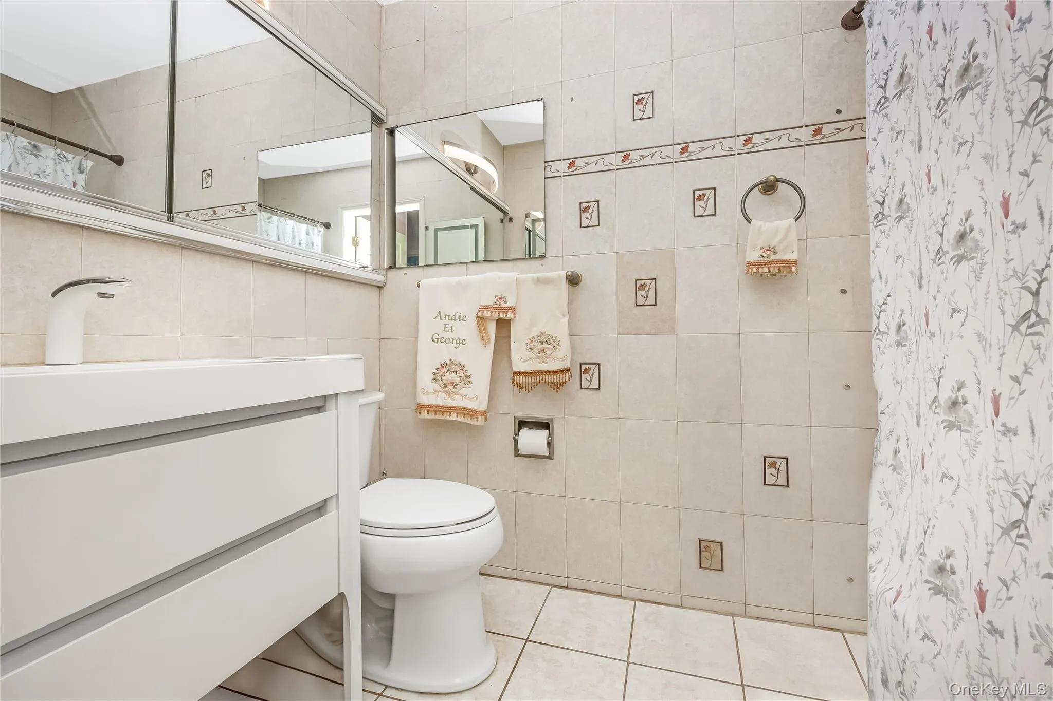 Full bathroom featuring vanity, tile walls, tile patterned floors, and a shower with curtain Full bathroom featuring vanity, tile walls, tile patterned floors, and a shower with curtain