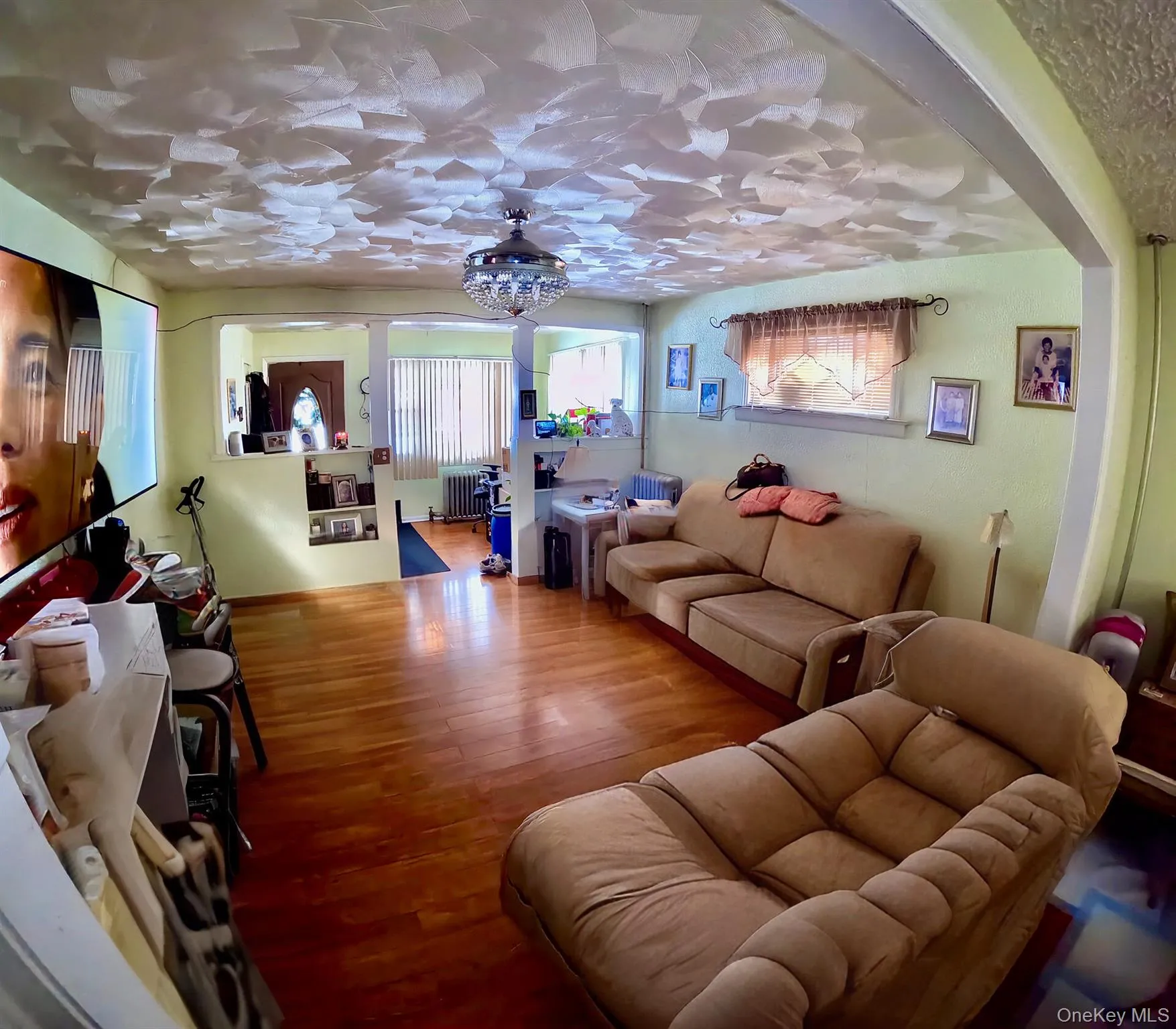 Living area with wood finished floors, radiator heating unit, and hanging lights Living area with wood finished floors, radiator heating unit, and hanging lights