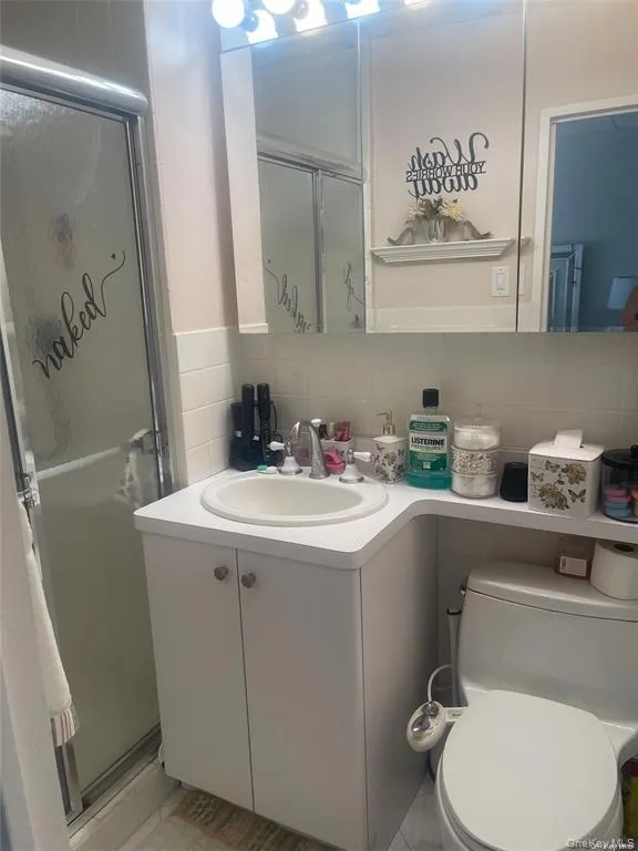 Bathroom featuring a shower stall, vanity, tasteful backsplash, and tile walls Bathroom featuring a shower stall, vanity, tasteful backsplash, and tile walls