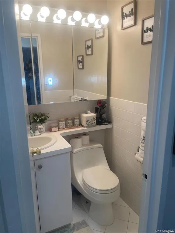 Half bath with light tile patterned floors, vanity, and tile walls Half bath with light tile patterned floors, vanity, and tile walls