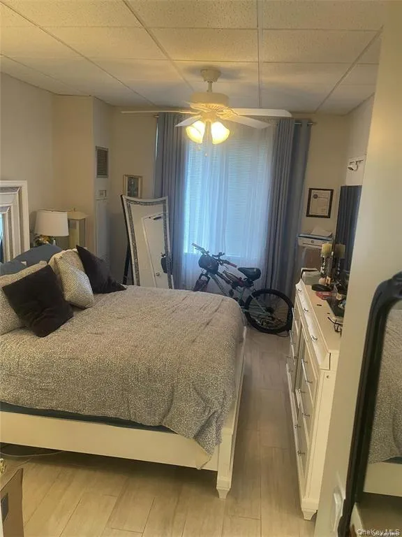 Bedroom with light wood-style floors, a ceiling fan, and a drop ceiling Bedroom with light wood-style floors, a ceiling fan, and a drop ceiling