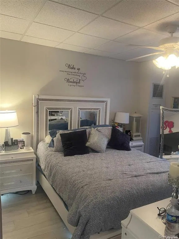 Bedroom featuring a paneled ceiling, light wood finished floors, and a ceiling fan Bedroom featuring a paneled ceiling, light wood finished floors, and a ceiling fan