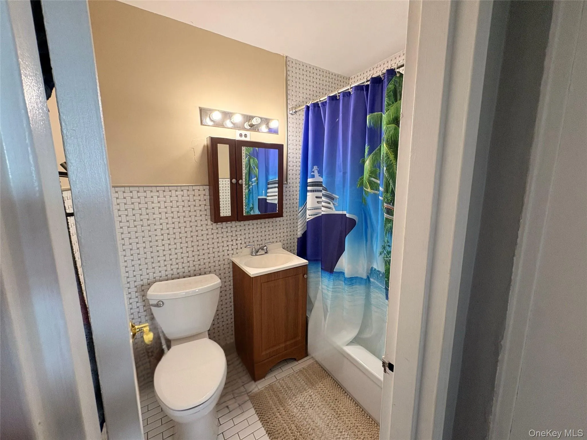 Bathroom with light tile patterned flooring, vanity, tile walls, and a wainscoted wall Bathroom with light tile patterned flooring, vanity, tile walls, and a wainscoted wall