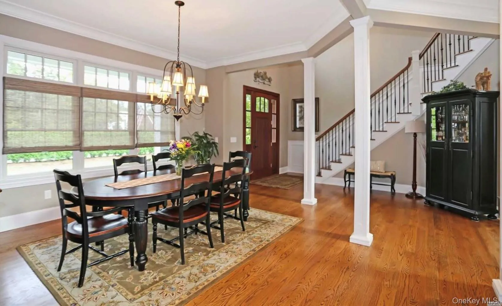 Dining area featuring stairway, ornamental molding, wood finished floors, and a chandelier Dining area featuring stairway, ornamental molding, wood finished floors, and a chandelier