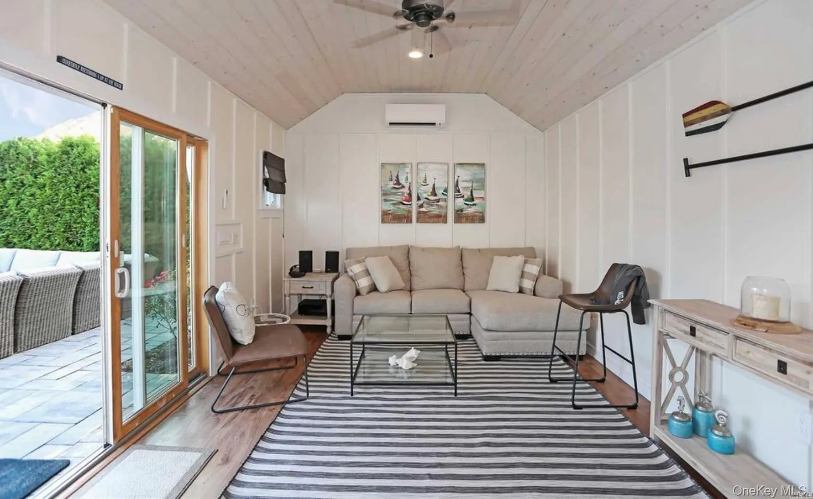 Living room with a decorative wall, wood finished floors, lofted ceiling, a wall unit AC, and a ceiling fan Living room with a decorative wall, wood finished floors, lofted ceiling, a wall unit AC, and a ceiling fan