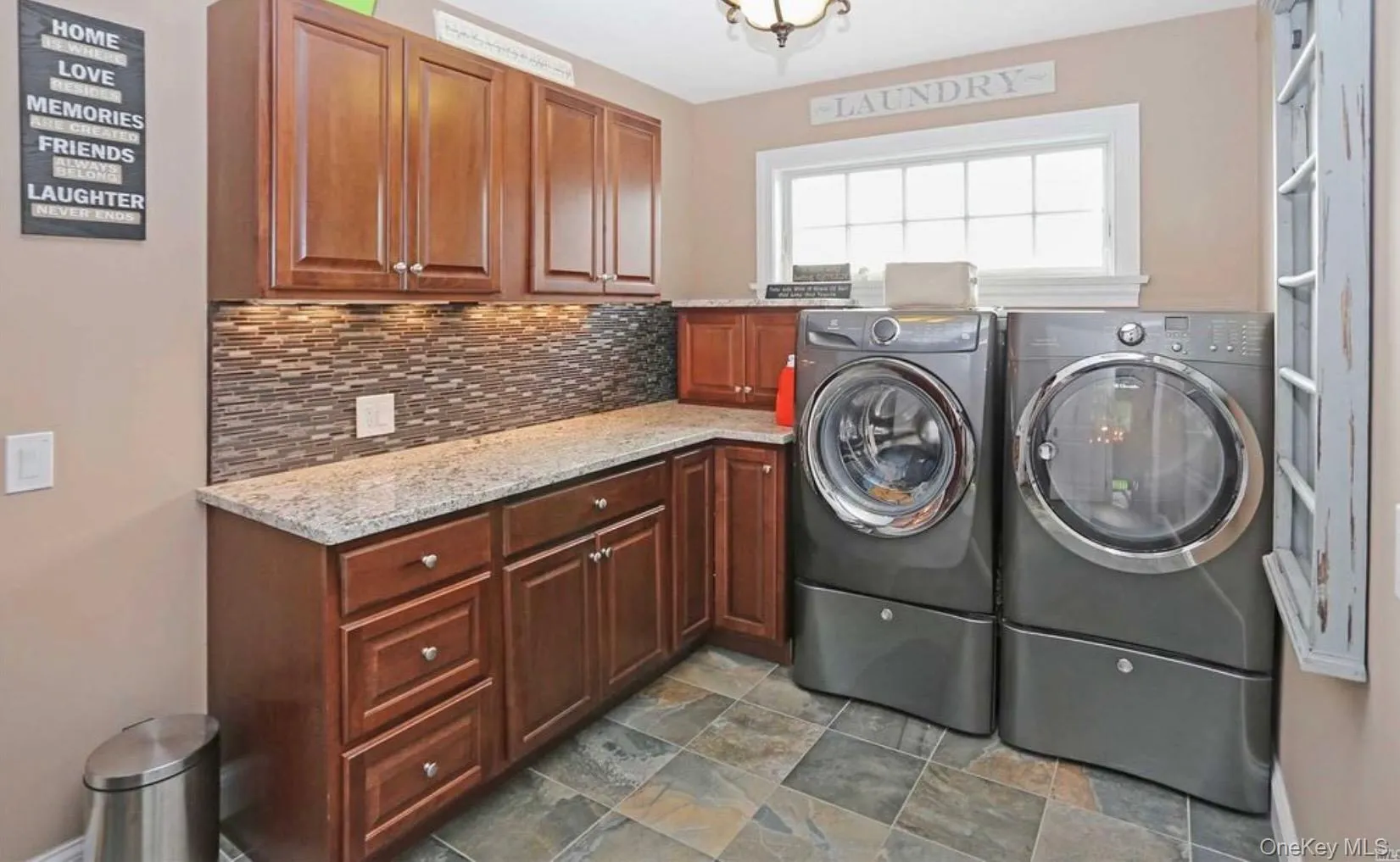 Laundry room with cabinet space, washing machine and dryer, and dark stone finish floors Laundry room with cabinet space, washing machine and dryer, and dark stone finish floors