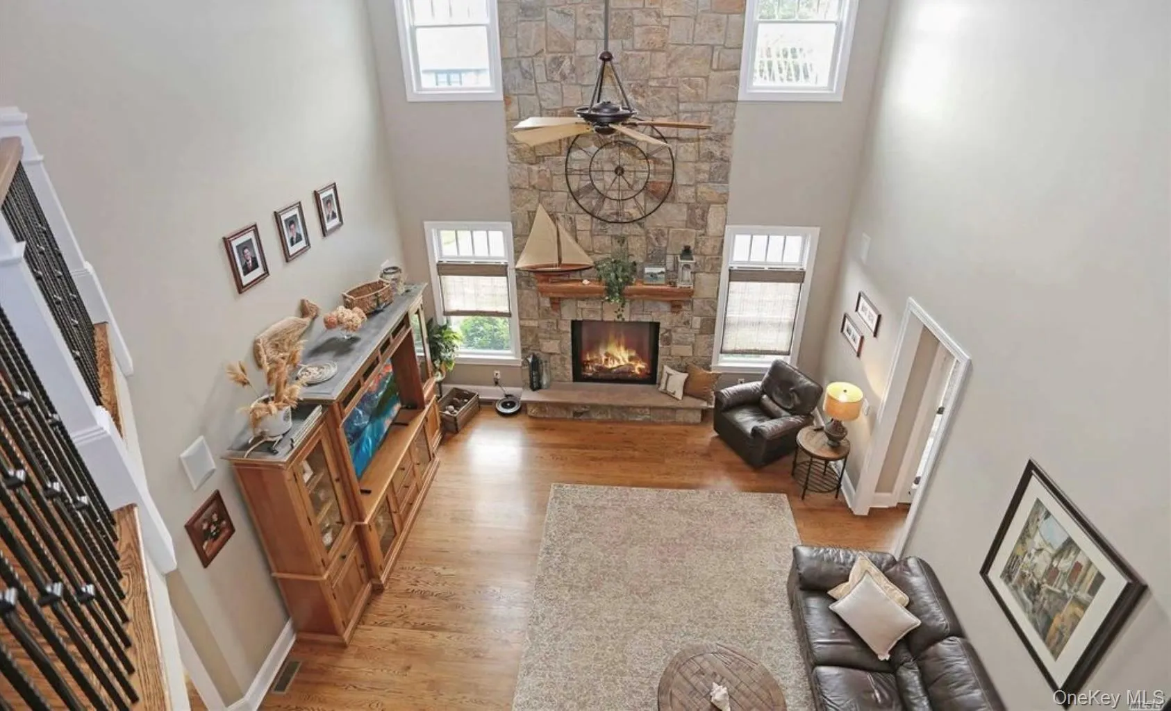 Living area with ceiling fan, a fireplace, a high ceiling, light wood-type flooring, and healthy amount of natural light Living area with ceiling fan, a fireplace, a high ceiling, light wood-type flooring, and healthy amount of natural light