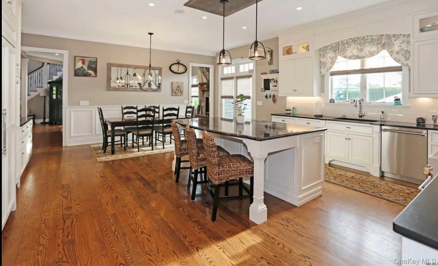 Kitchen featuring a breakfast bar area, pendant lighting, a center island, white cabinets, and dishwasher Kitchen featuring a breakfast bar area, pendant lighting, a center island, white cabinets, and dishwasher