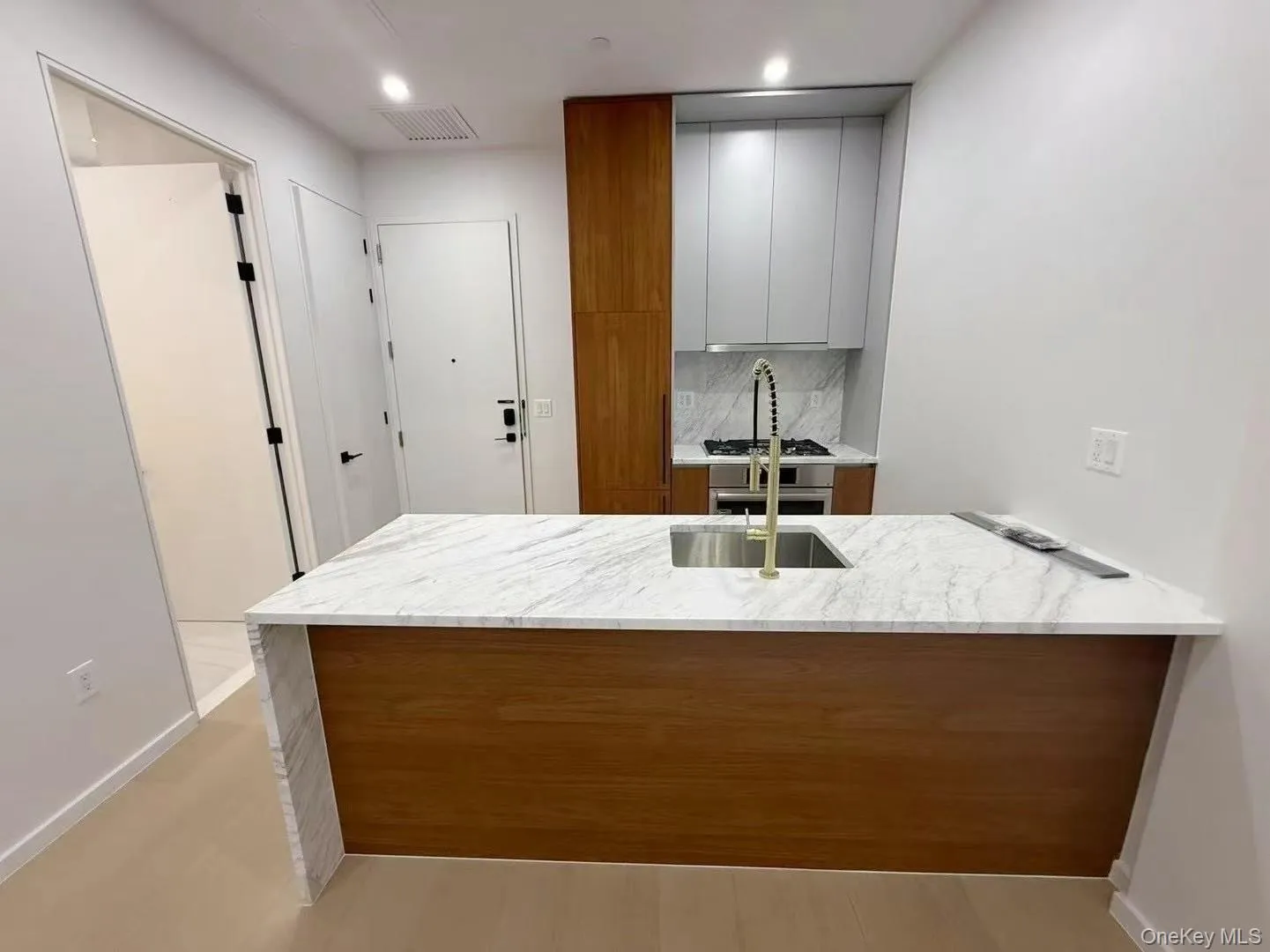 Kitchen featuring modern cabinets, light stone counters, backsplash, a peninsula, and recessed lighting Kitchen featuring modern cabinets, light stone counters, backsplash, a peninsula, and recessed lighting