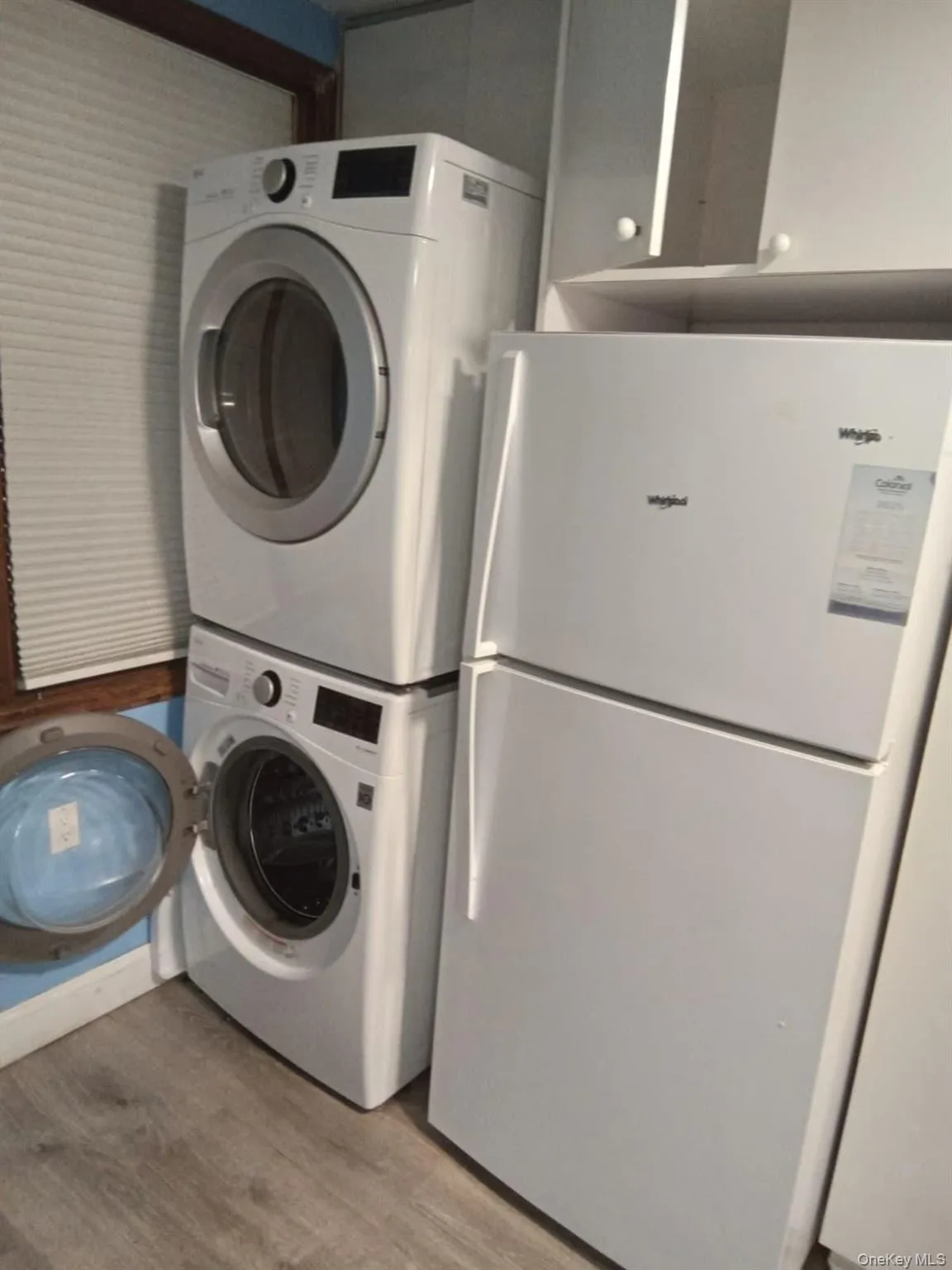 Laundry room featuring light wood-style flooring and stacked washer and clothes dryer Laundry room featuring light wood-style flooring and stacked washer and clothes dryer