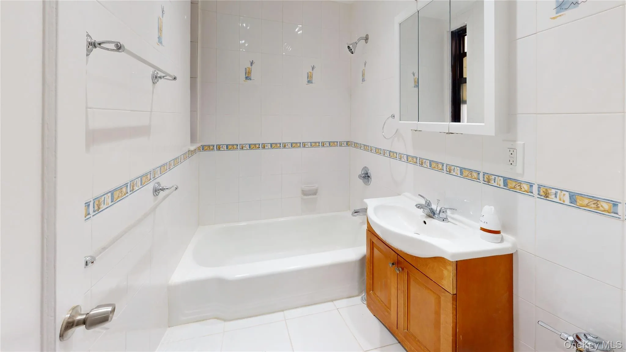 Full bath featuring tile walls, vanity, light tile patterned floors, and bathing tub / shower combination Full bath featuring tile walls, vanity, light tile patterned floors, and bathing tub / shower combination
