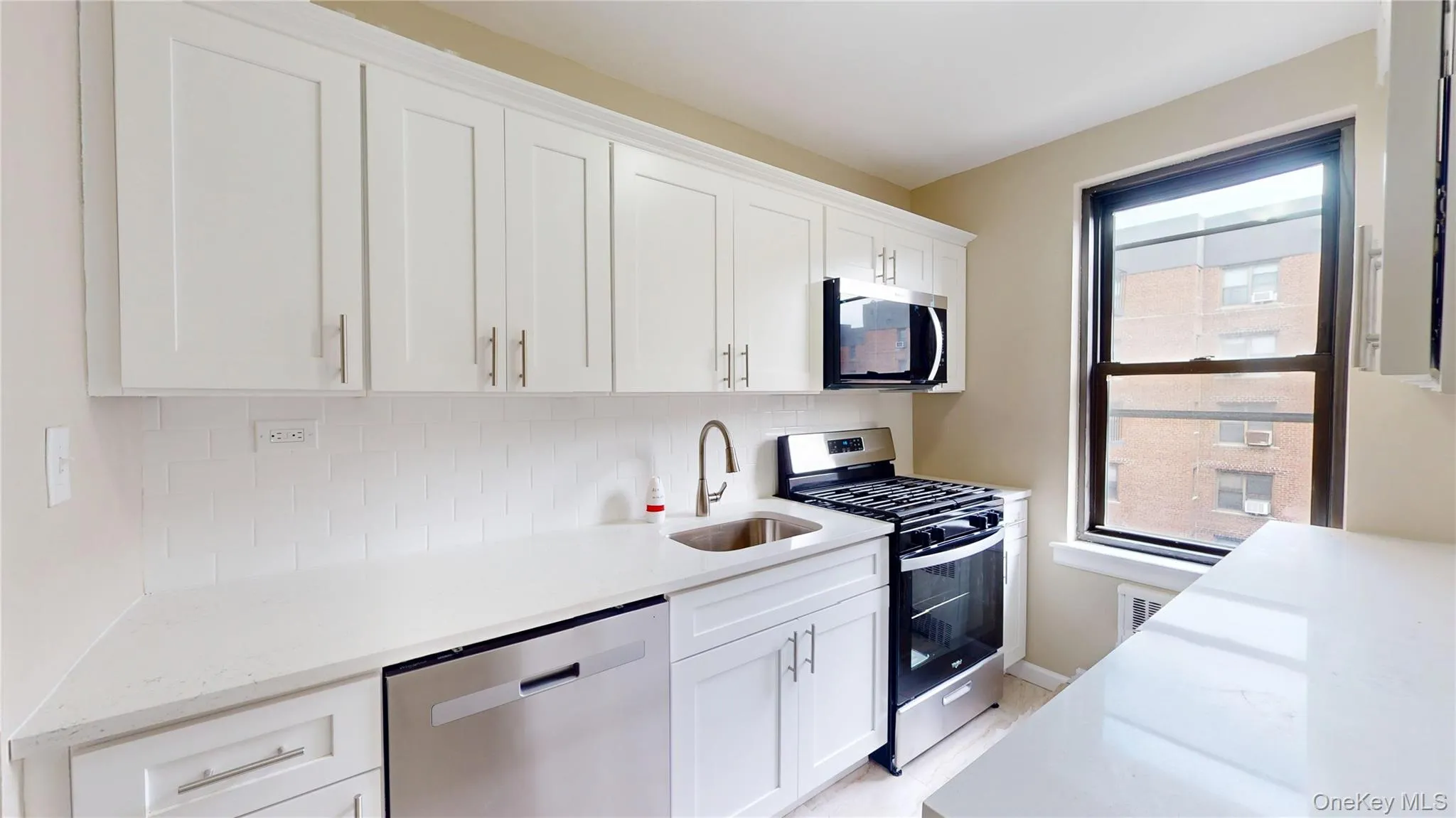 Kitchen featuring stainless steel appliances, tasteful backsplash, white cabinets, and light stone countertops Kitchen featuring stainless steel appliances, tasteful backsplash, white cabinets, and light stone countertops