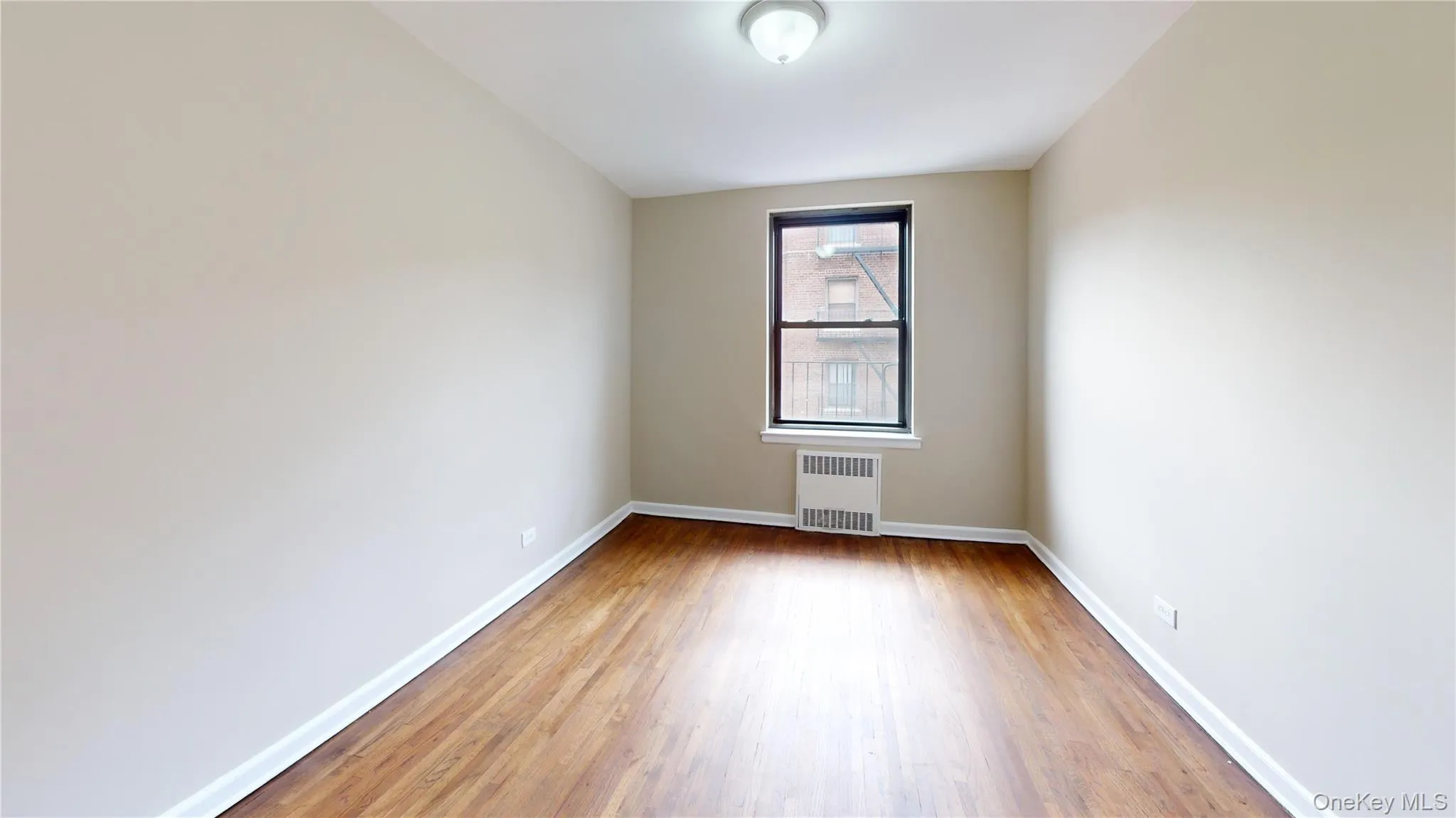 Empty room with radiator and light wood-style floors Empty room with radiator and light wood-style floors