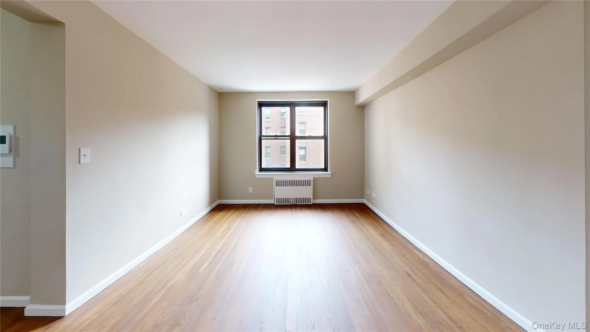 Empty room with wood finished floors and radiator heating unit Empty room with wood finished floors and radiator heating unit