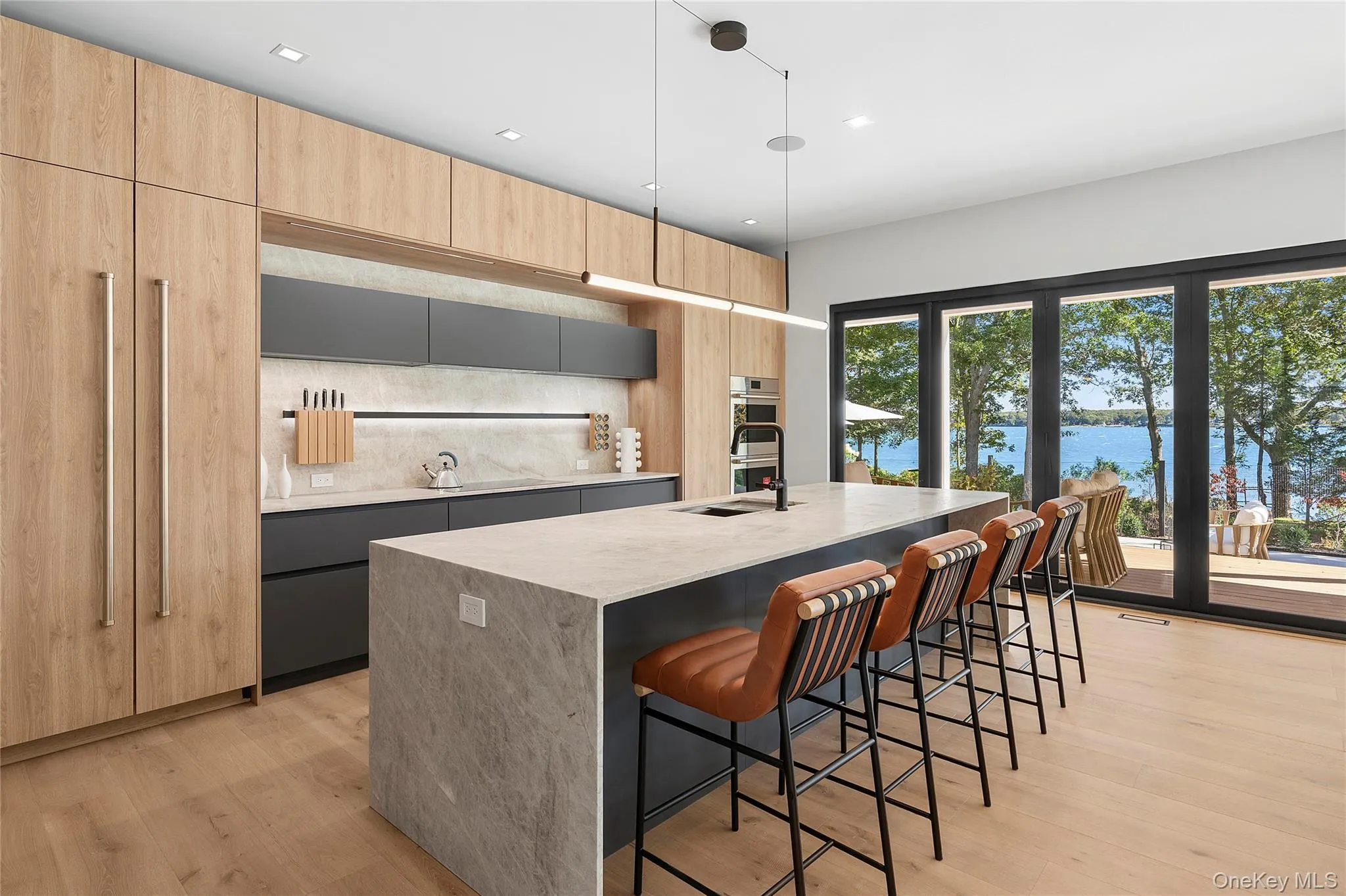 Kitchen with a breakfast bar, modern cabinets, light wood-style flooring, light brown cabinetry, and decorative light fixtures Kitchen with a breakfast bar, modern cabinets, light wood-style flooring, light brown cabinetry, and decorative light fixtures