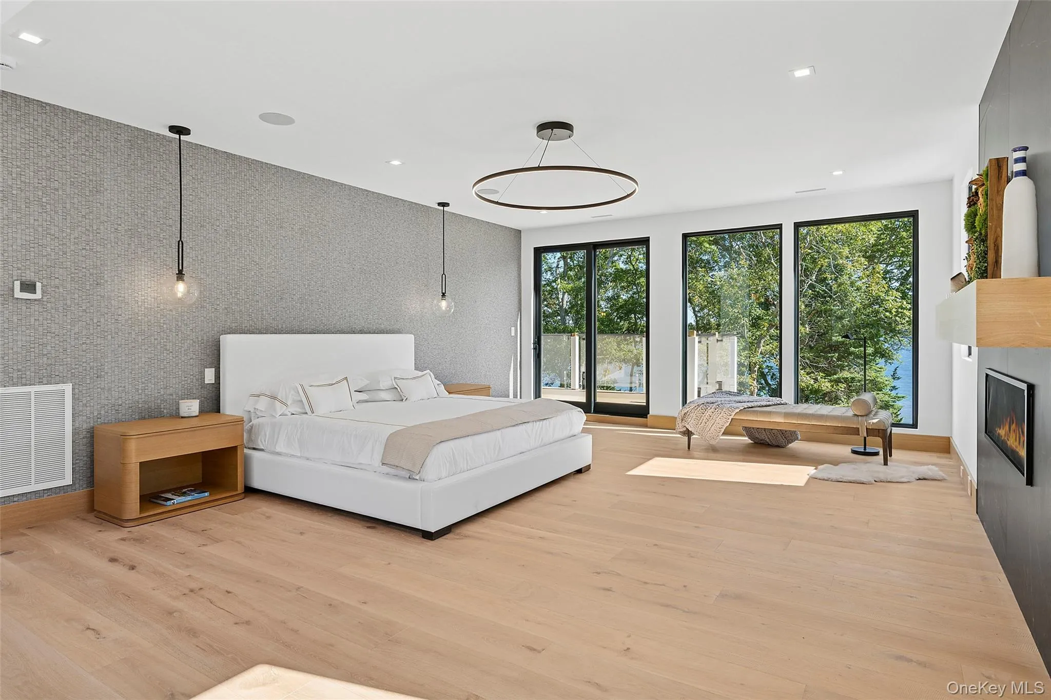Bedroom with a glass covered fireplace, an accent wall, light wood-type flooring, recessed lighting, and wallpapered walls Bedroom with a glass covered fireplace, an accent wall, light wood-type flooring, recessed lighting, and wallpapered walls