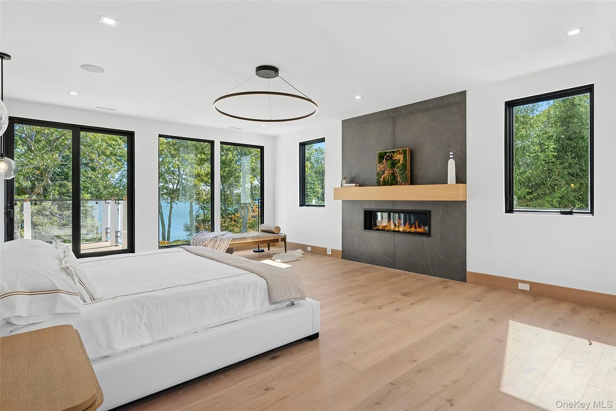 Bedroom with multiple windows, light wood-style flooring, a fireplace, and recessed lighting Bedroom with multiple windows, light wood-style flooring, a fireplace, and recessed lighting
