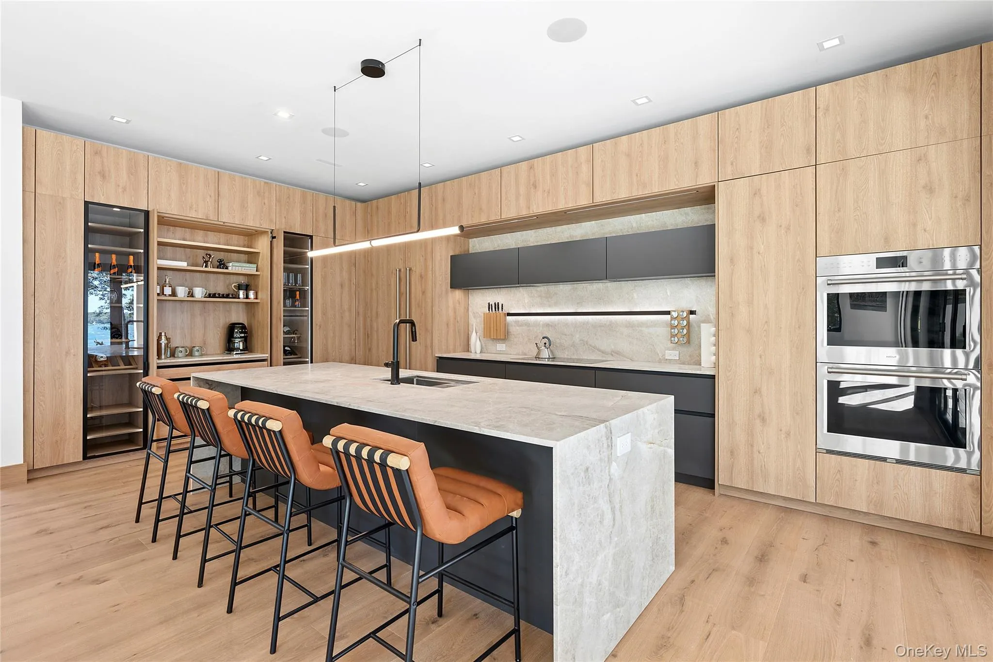 Kitchen with light brown cabinets, open shelves, a breakfast bar, modern cabinets, and double oven Kitchen with light brown cabinets, open shelves, a breakfast bar, modern cabinets, and double oven