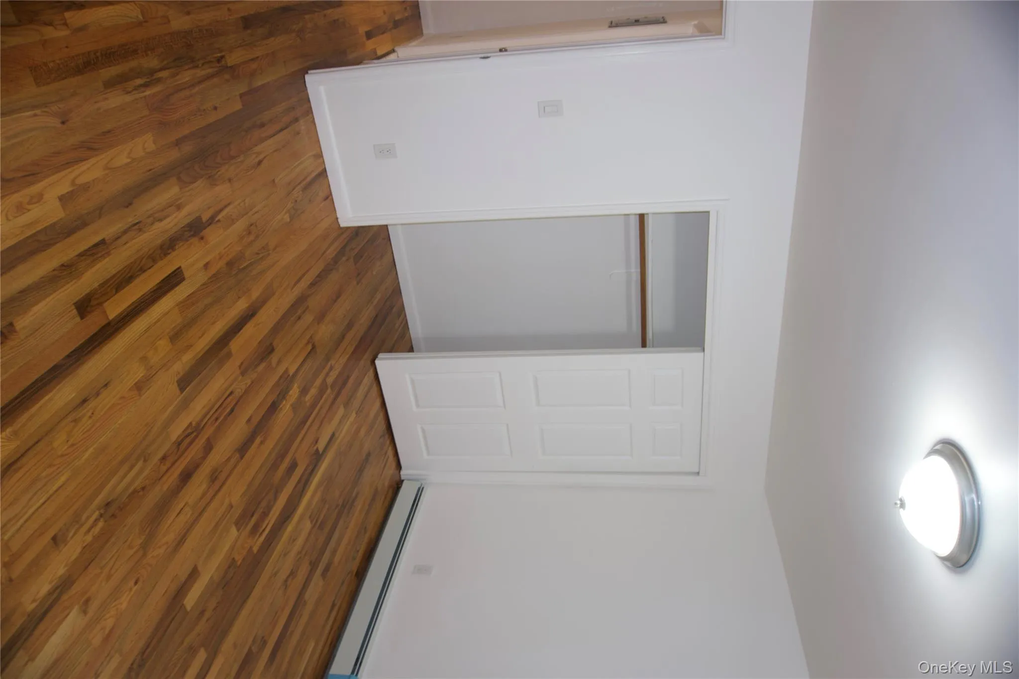 Unfurnished bedroom featuring a baseboard heating unit, dark wood-style flooring, and a closet Unfurnished bedroom featuring a baseboard heating unit, dark wood-style flooring, and a closet