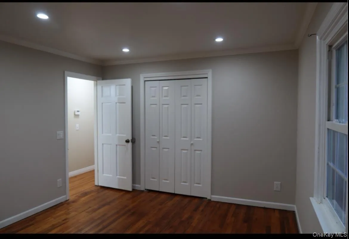 Unfurnished bedroom with crown molding, dark wood finished floors, recessed lighting, and a closet Unfurnished bedroom with crown molding, dark wood finished floors, recessed lighting, and a closet