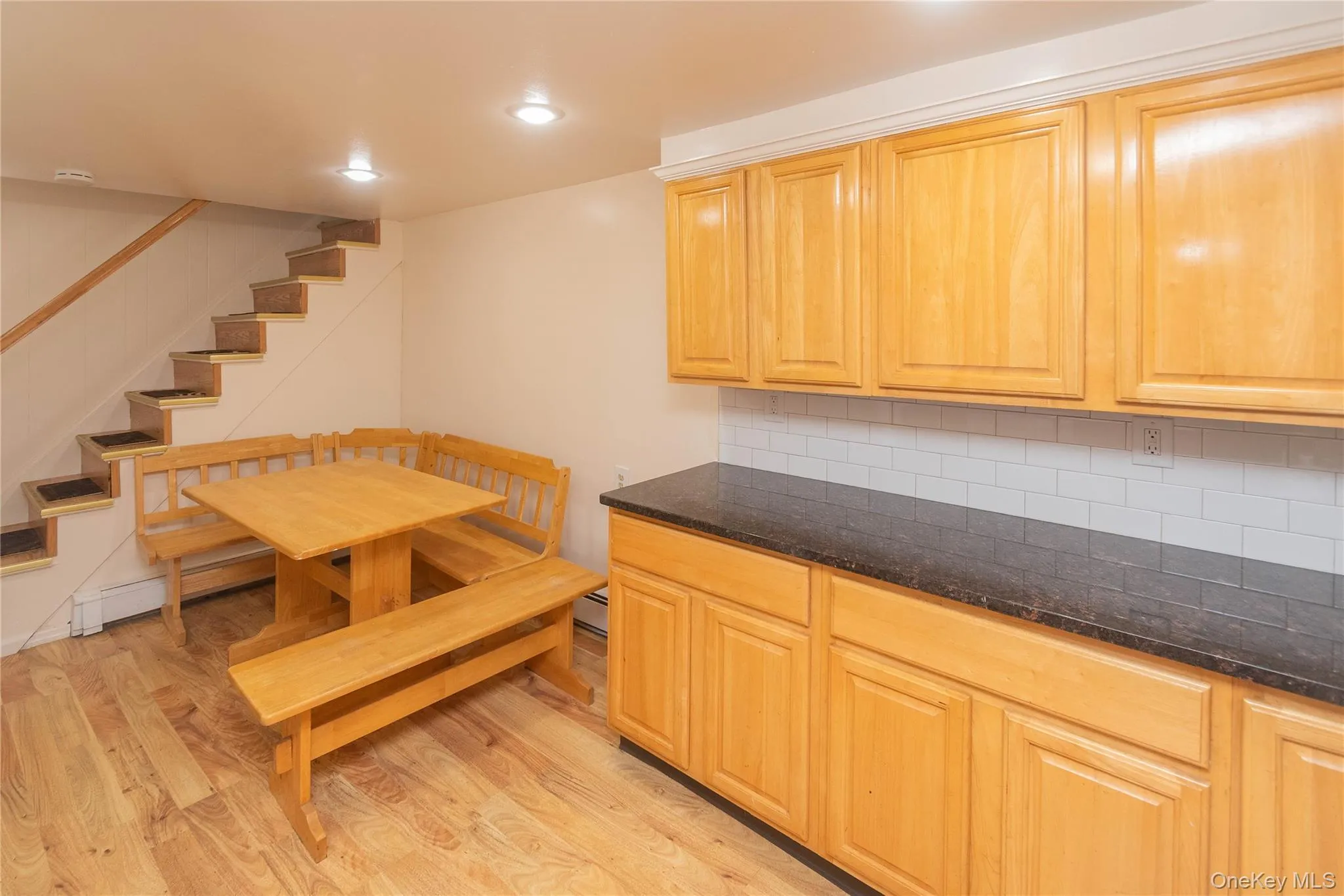 Kitchen with light wood-style flooring, decorative backsplash, dark stone countertops, a baseboard heating unit, and recessed lighting Kitchen with light wood-style flooring, decorative backsplash, dark stone countertops, a baseboard heating unit, and recessed lighting