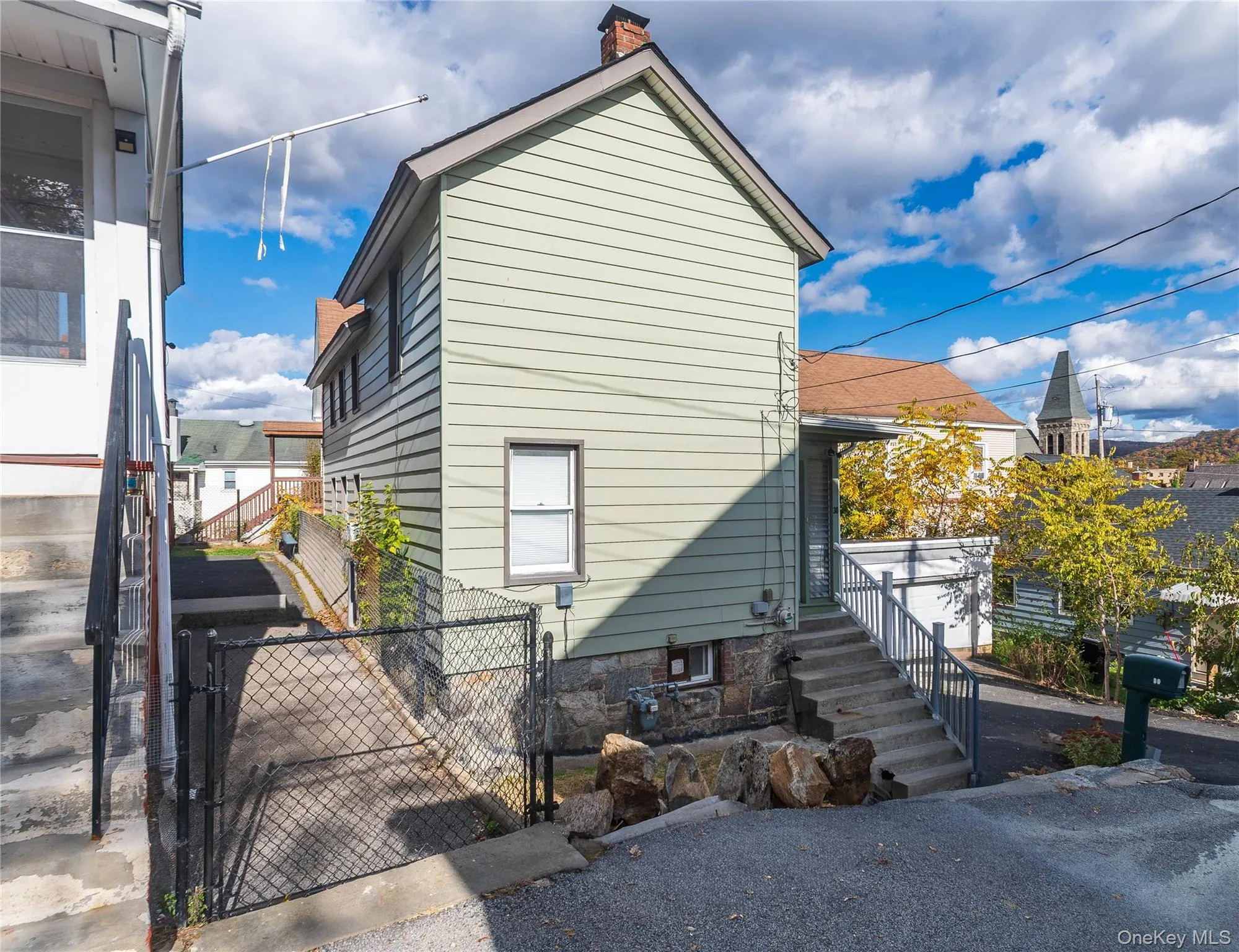 View of side of home featuring a gate and a chimney View of side of home featuring a gate and a chimney