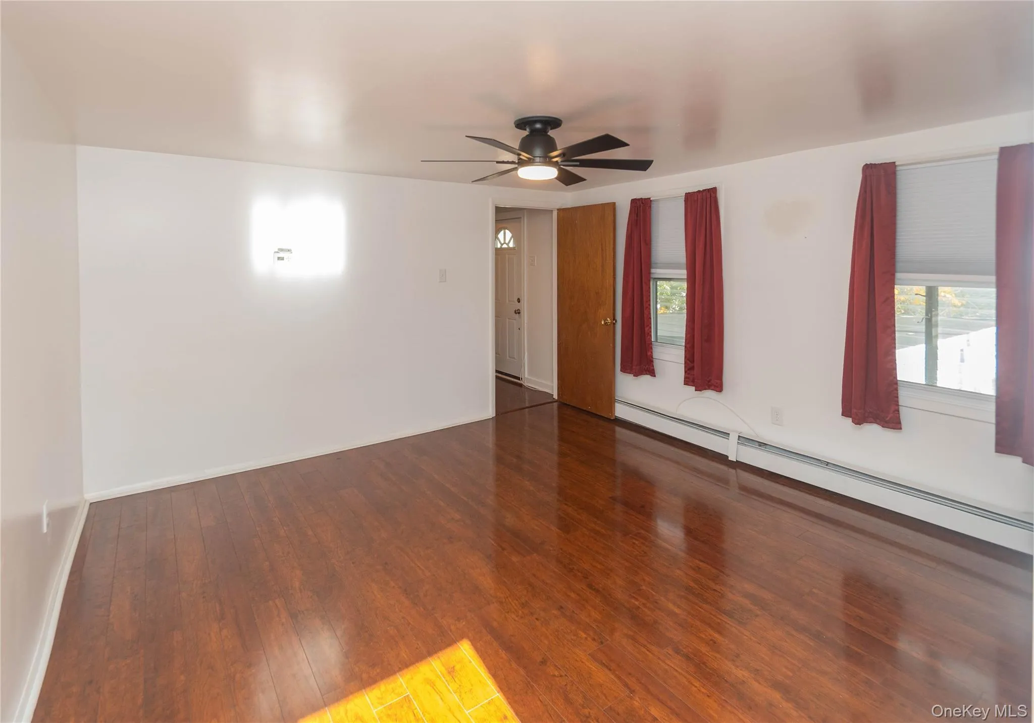 Spare room featuring a baseboard heating unit, hardwood / wood-style floors, and ceiling fan Spare room featuring a baseboard heating unit, hardwood / wood-style floors, and ceiling fan