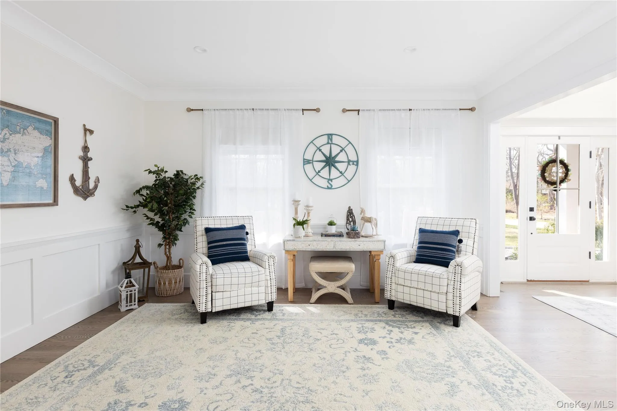 Living area with wood finished floors, ornamental molding, wainscoting, and a decorative wall Living area with wood finished floors, ornamental molding, wainscoting, and a decorative wall